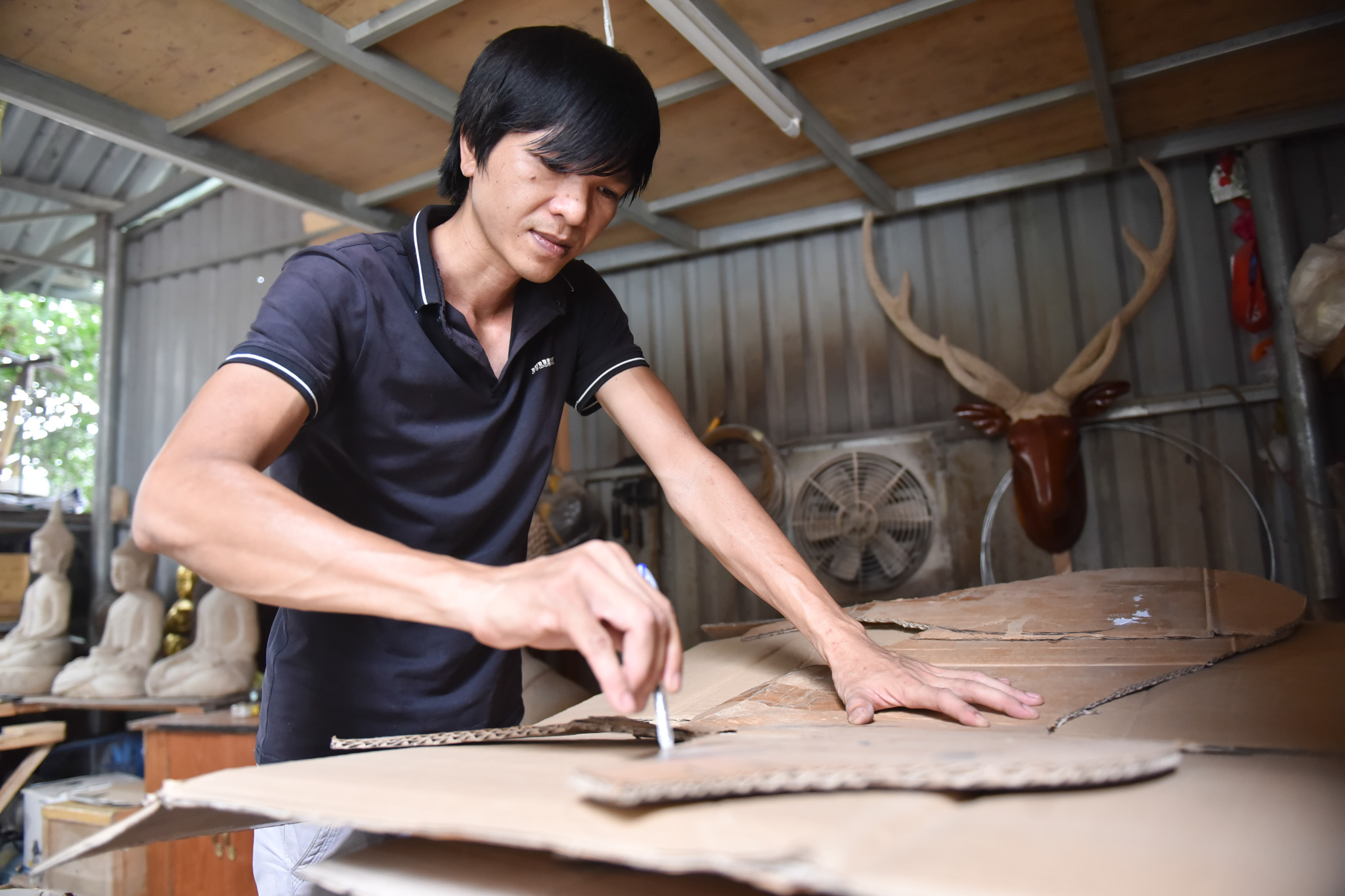 Nguyen Hoang Hai draws the shape of an animal on cardboard paper before creating a sculpture out of it. Photo: Ngoc Phuong / Tuoi Tre News