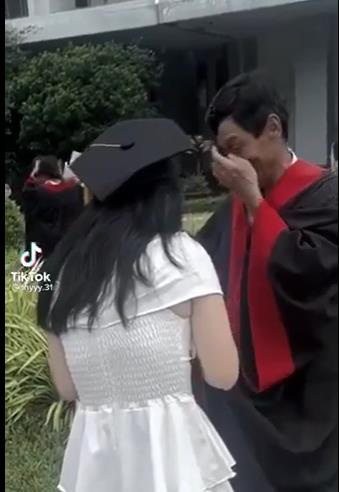 Le Thi Kim Thy’s father wipes tears from his cheek on her graduation day.