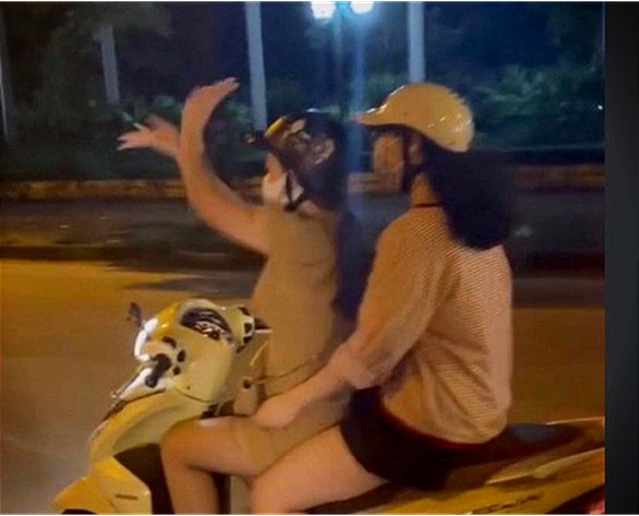 Young woman fined for doing hand fan dance while riding motorbike in Hanoi