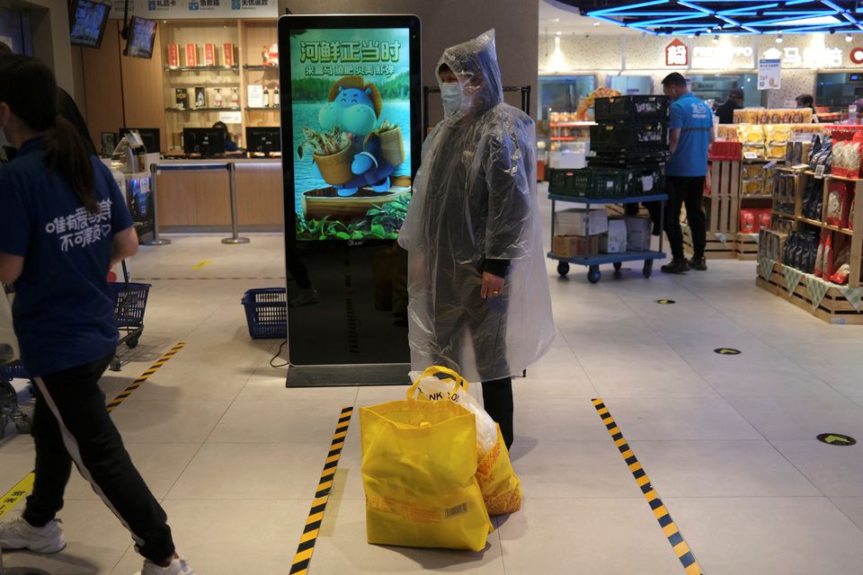 A customer wearing a raincoat waits at a check-out counter at a supermarket, following the coronavirus disease (COVID-19) outbreak, in Beijing, China April 27, 2022. Photo: Reuters