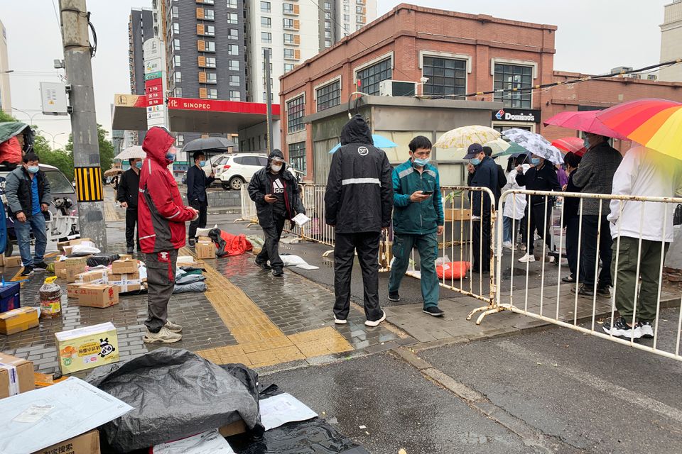 People line up for nucleic acid testing at a site where delivery workers stand outside the barricades marking an area under lockdown following the coronavirus disease (COVID-19) outbreak, in Chaoyang district of Beijing, China April 27, 2022. Photo: Reuters