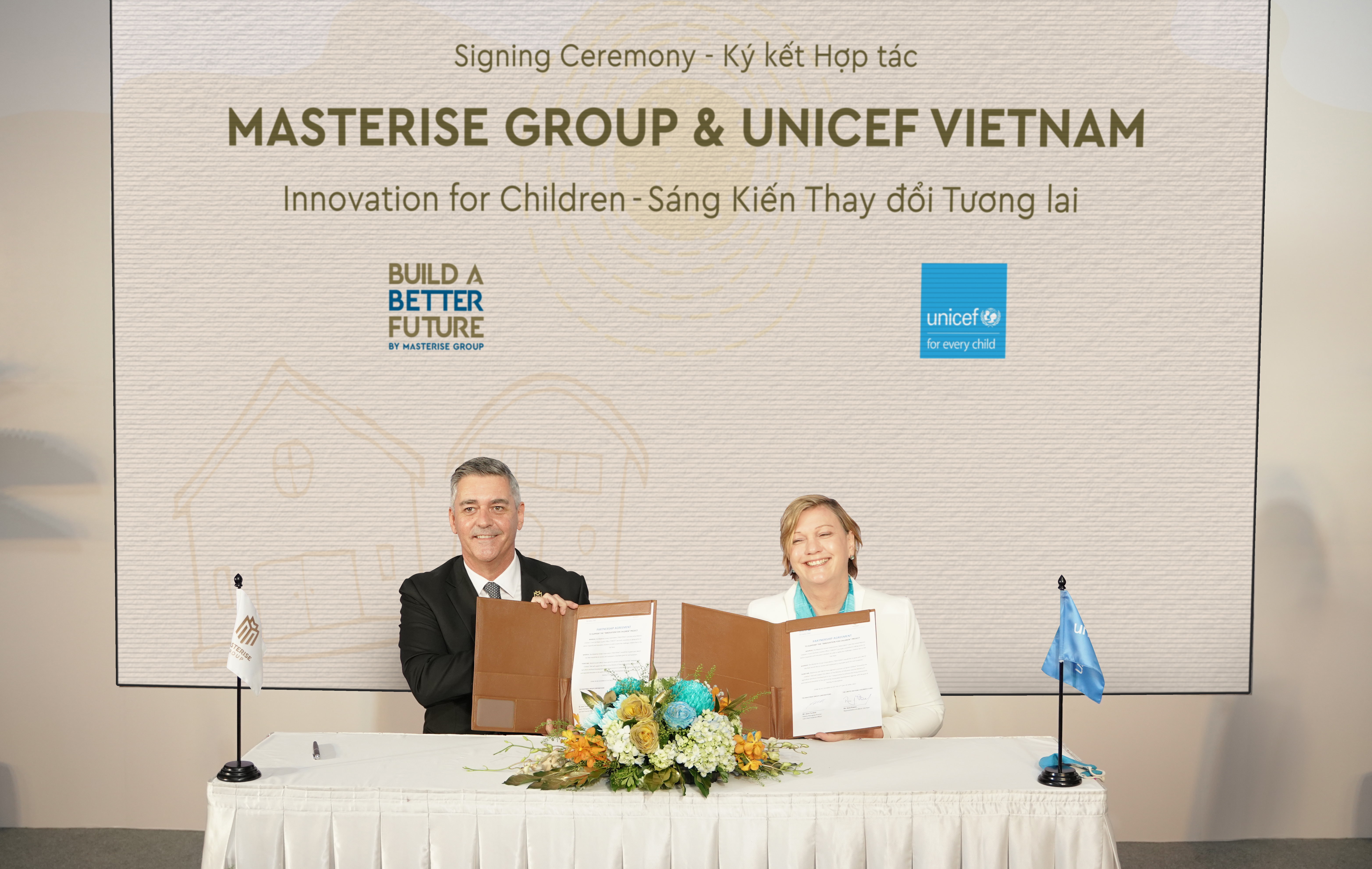 Jason Turnbull (L), Deputy Managing Director and Chief Financial Officer of Masterise Homes, signs a partnership deal with Rana Flowers, UNICEF Representative to Vietnam.