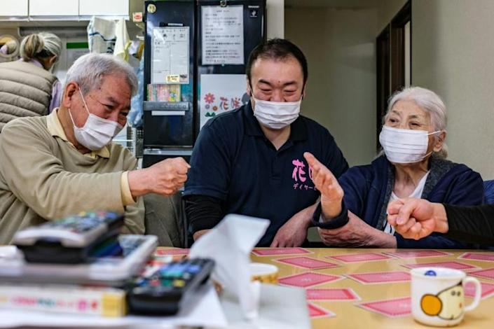 This picture taken on March 30, 2022 shows retired sumo wrestler and staff member Shuji Nakaita (C) taking care of elderly people at the Hanasaki daycare centre in Tokyo. Photo: AFP