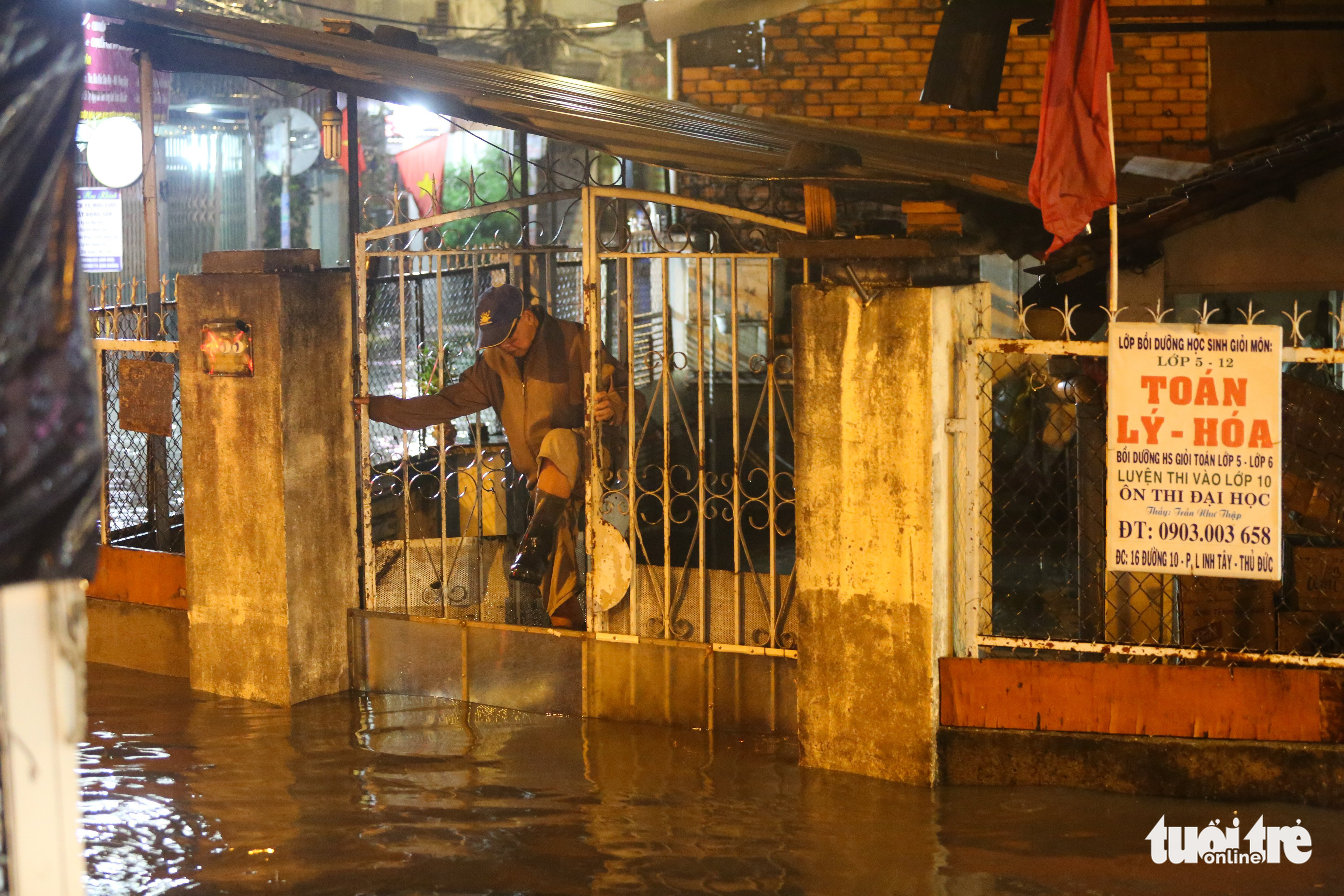 A man uses a glass board to block rainwater in Thu Duc City, Ho Chi Minh City, April 29, 2022. Photo: Chau Tuan / Tuoi Tre