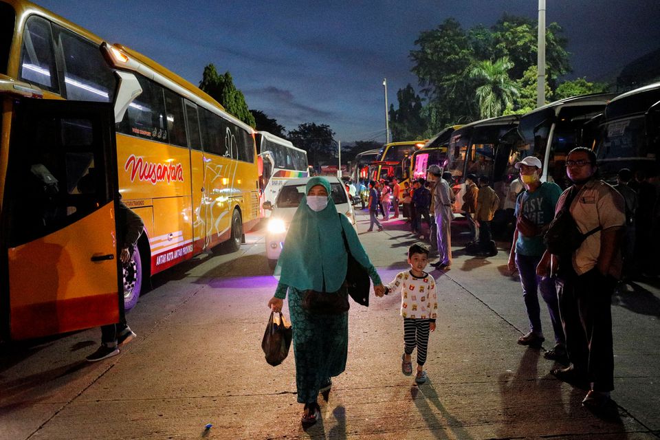 A woman walks with a child at Kampung Rambutan bus terminal, as Indonesian Muslims travel home to celebrate Eid al-Fitr, known locally as 'Mudik', in Jakarta, Indonesia, April 29, 2022. Photo: Reuters
