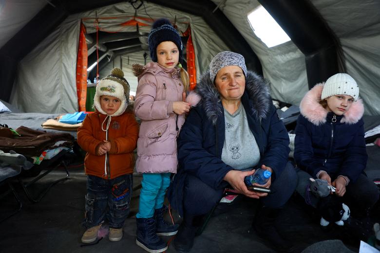 A Ukrainian family from Mykolaiv sit inside a tent to warm up after crossing the border from Ukraine to Poland, at the border checkpoint in Medyka, Poland, March 20, 2022. Photo: Reuters