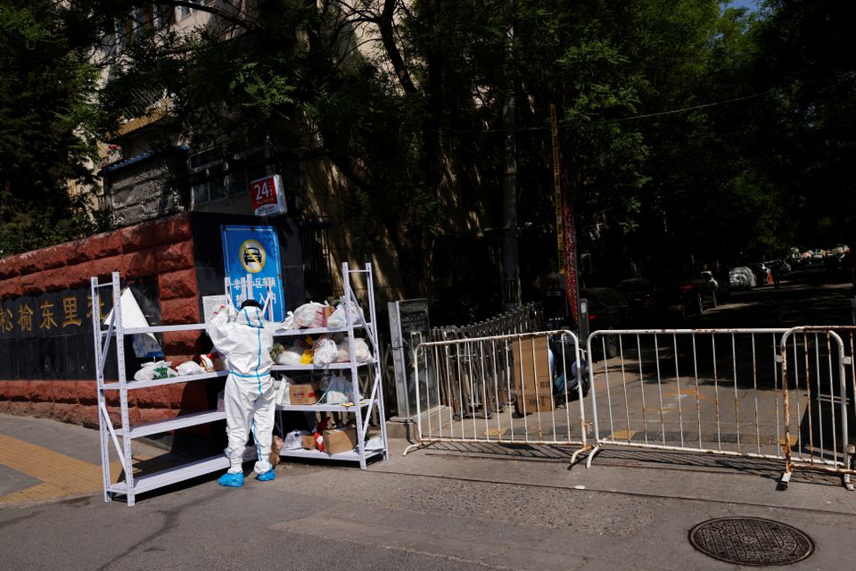 A worker in a protective suit sorts deliveries on a rack outside an area under lockdown, amid the coronavirus disease (COVID-19) outbreak, in Beijing, China May 2, 2022. Photo: Reuters
