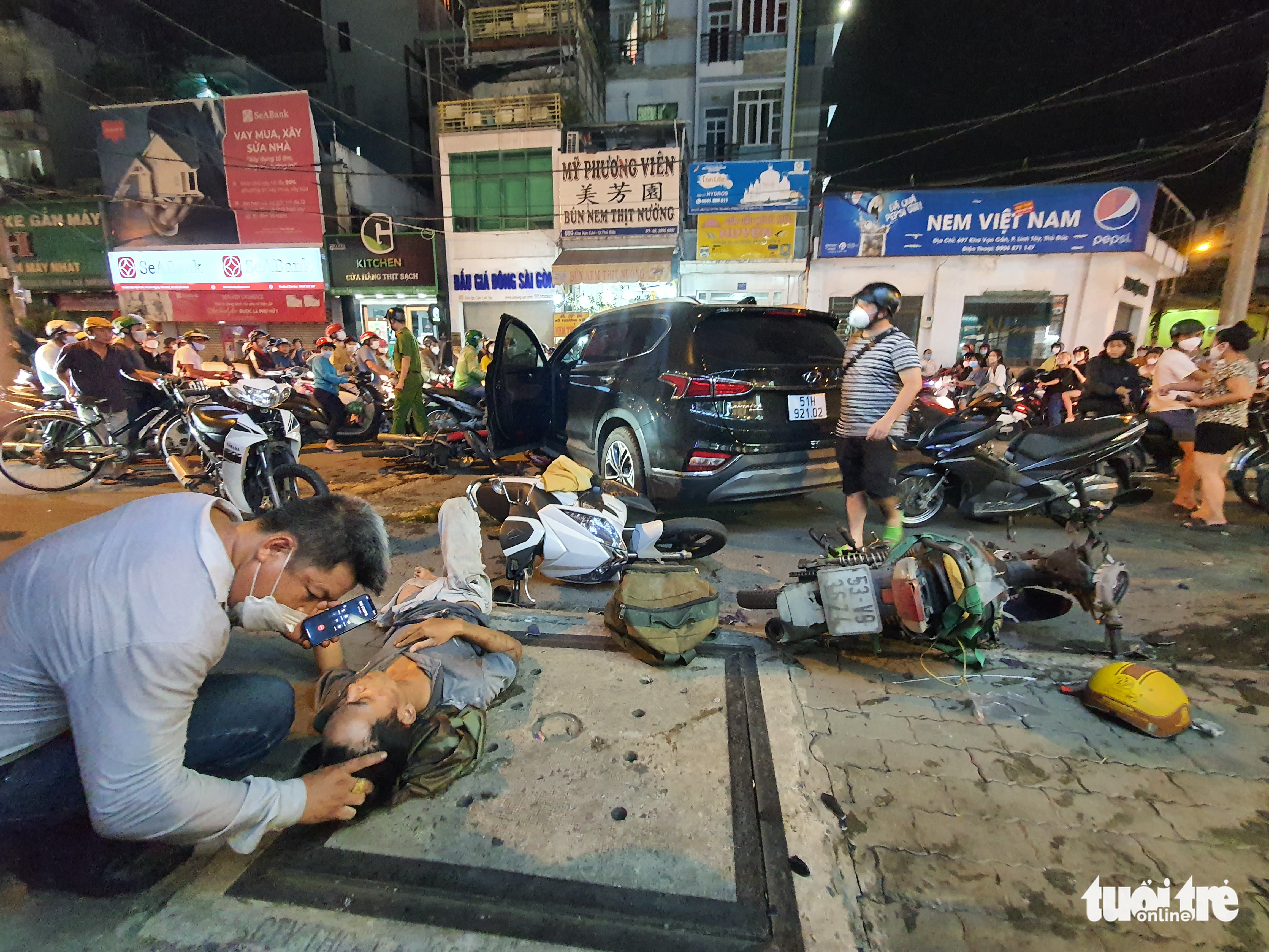 A man talks with an injured victim on the sidewalk following the crash in Thu Duc City, Ho Chi Minh City, May 5, 2022. Photo: Minh Hoa / Tuoi Tre