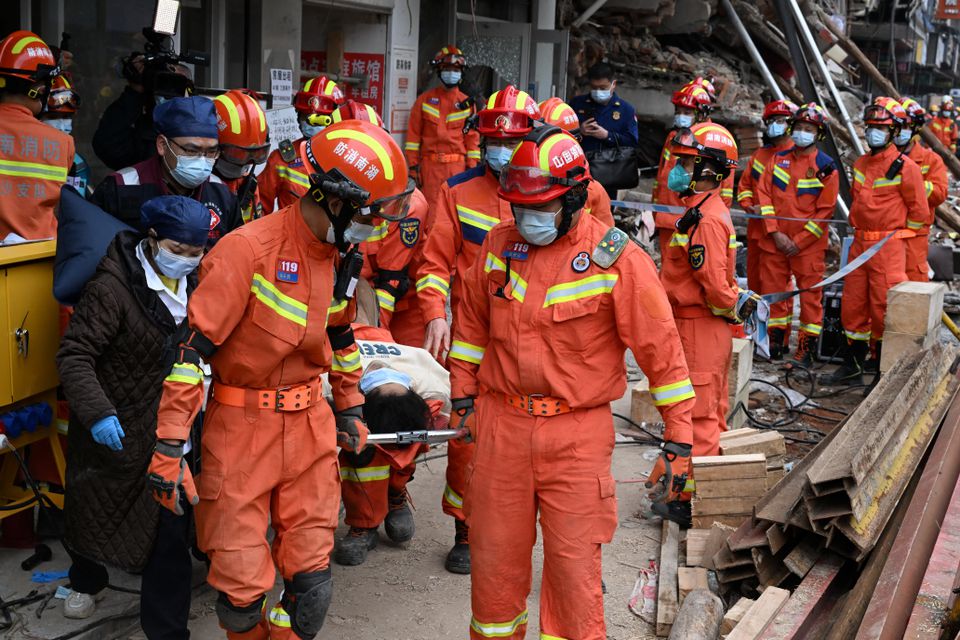 Rescue workers carry an injured person on a stretcher at a site where a building collapsed in Changsha, Hunan province, China May 1, 2022. China Daily/via Reuters