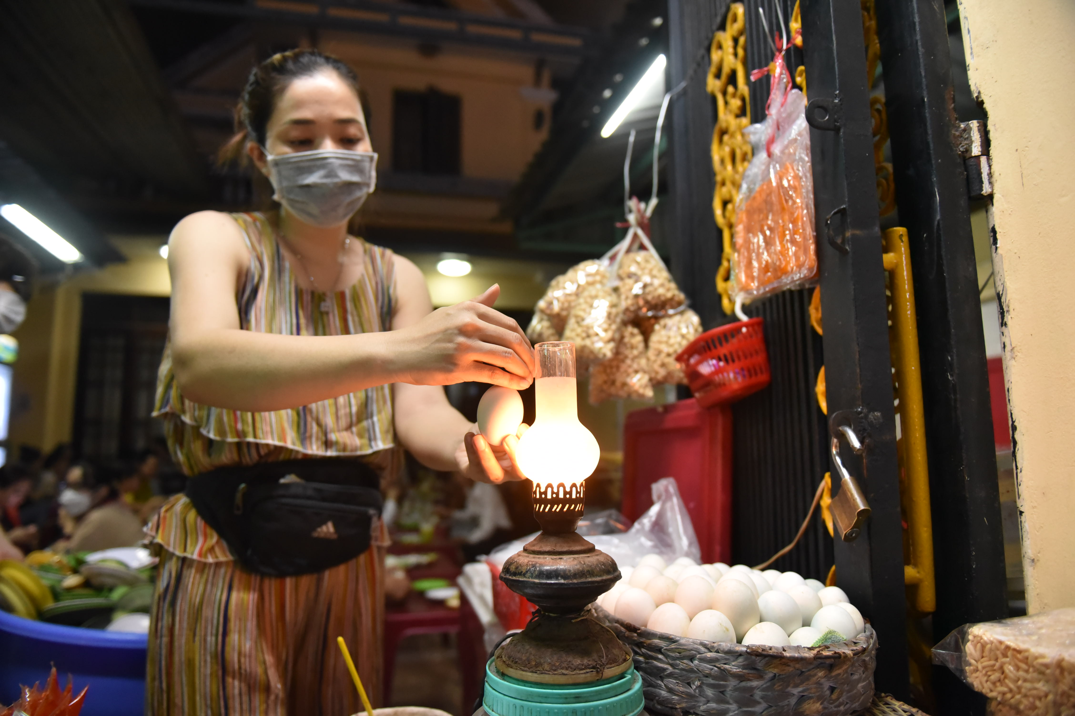 Pham Kim Tinh is seen with an oil lamp passed from her parents at her balut stall in Thao Dien Ward, Thu Duc City. Photo: Ngoc Phuong / Tuoi Tre News