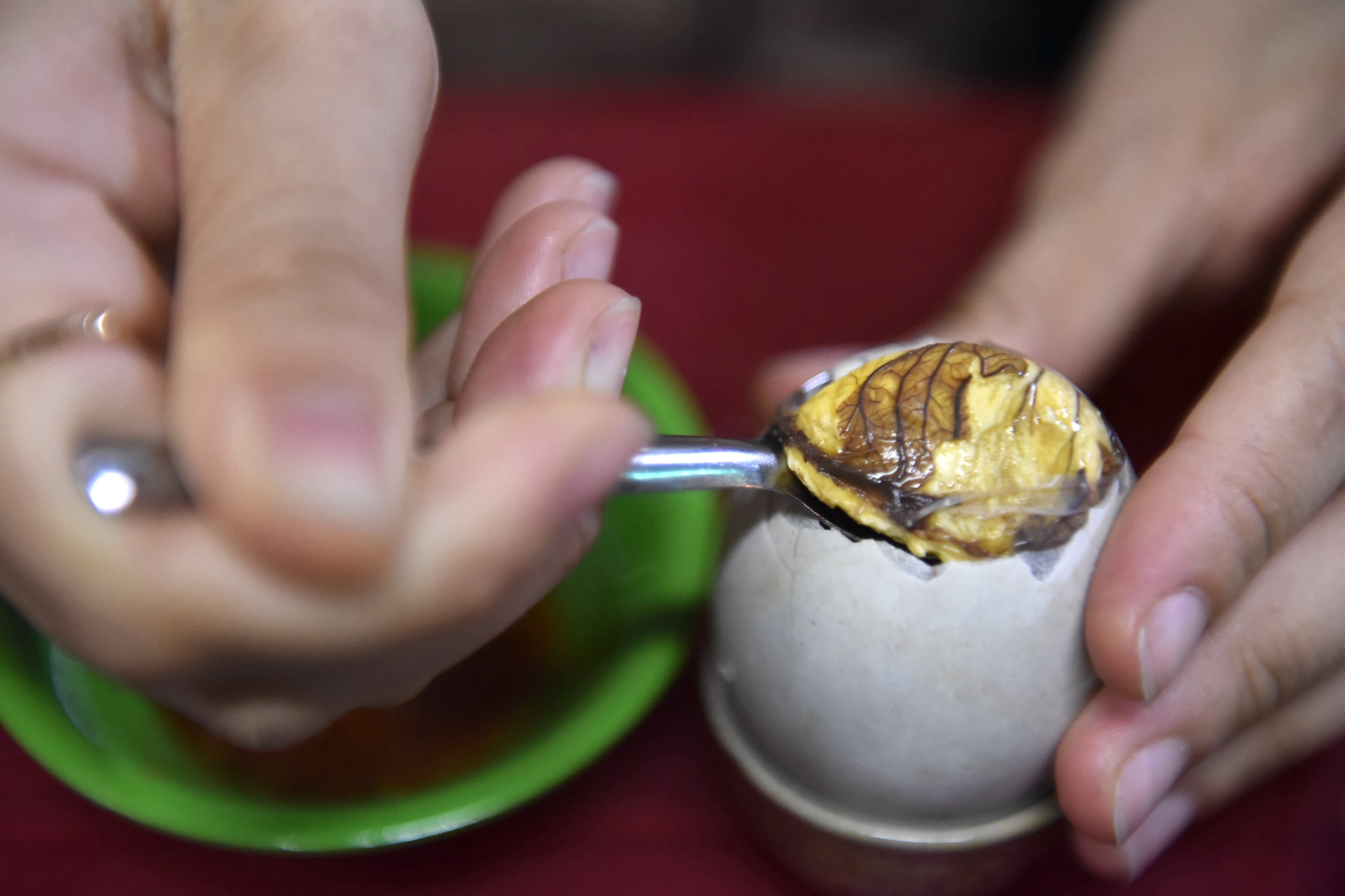 A diner scoops balut out of the eggshell. Photo: Ngoc Phuong / Tuoi Tre News