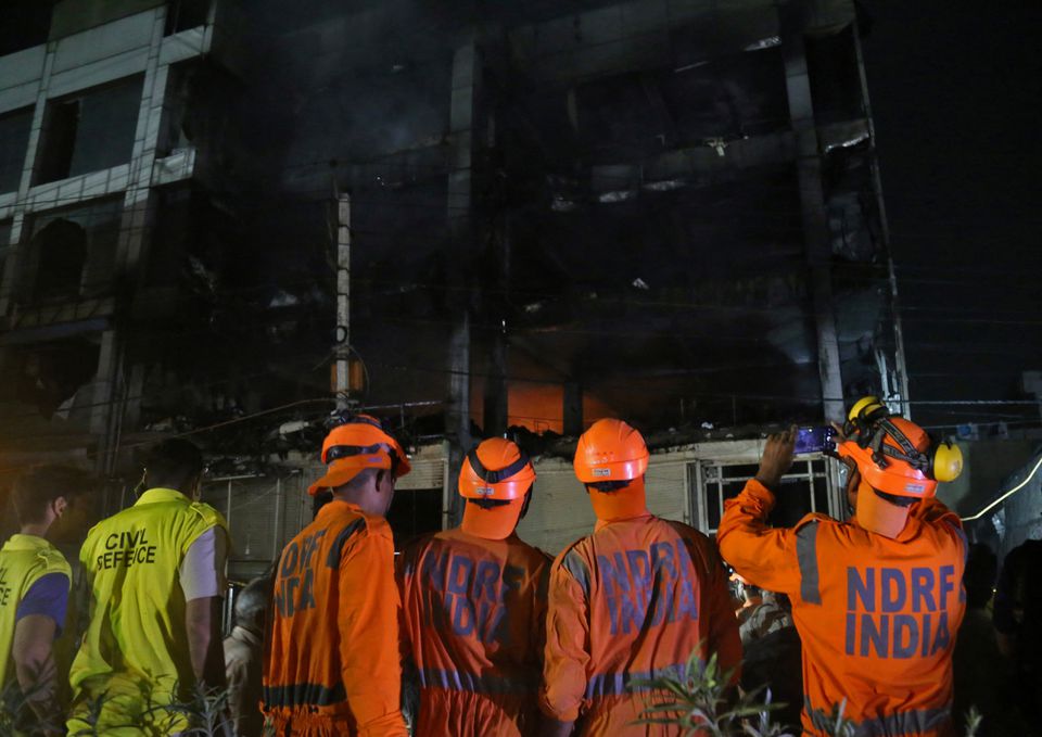 Members of the National Disaster Response Force (NDRF) stand as fire fighters try to douse a fire that broke out at a commercial building in Delhi's western suburb, India May 13, 2022. Photo: Reuters