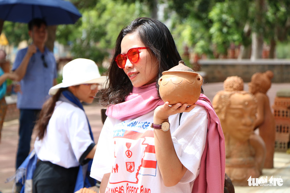 A visitor poses with a pottery product in Bau Truc Village, Ninh Thuan Province, Vietnam. Photo: Duy Ngoc / Tuoi Tre