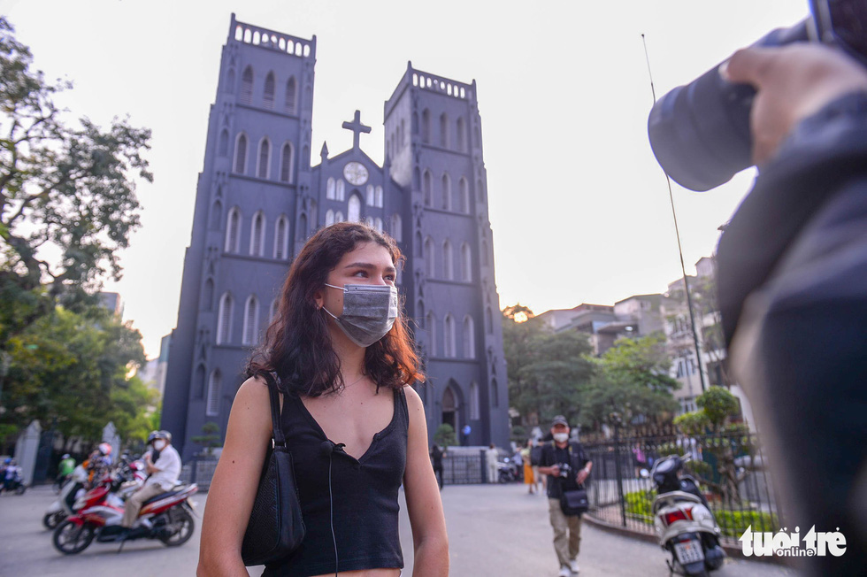 A foreign visitor poses for a photo against the background of the Hanoi St. Joseph's Cathedral. Photo: Ha Quan / Tuoi Tre