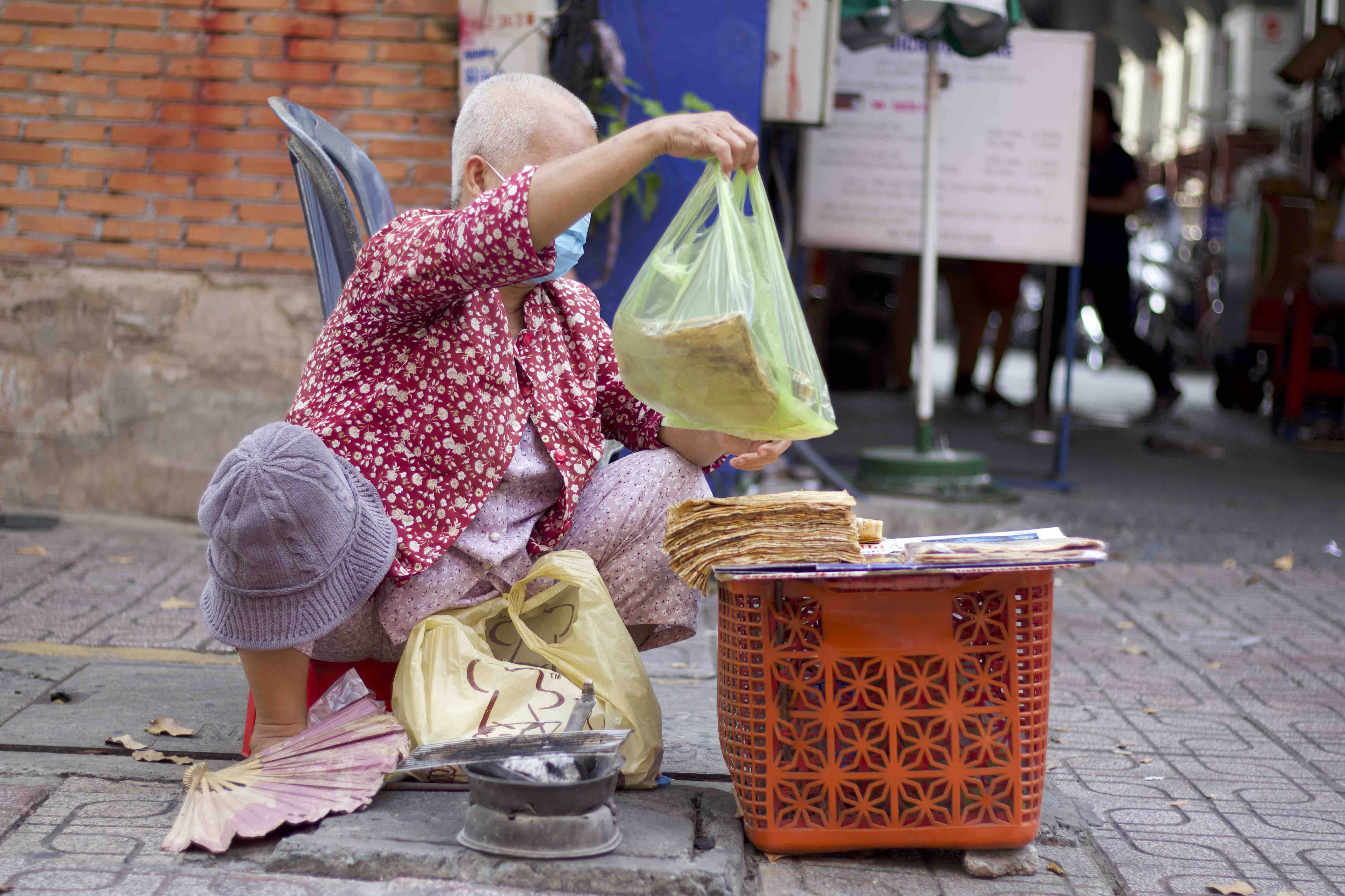 Nguyen Thi Loi packages banh chuoi nuong into plastic bag for her customers. Photo: Linh To / Tuoi Tre