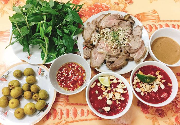 A dish of 'de nui' (mountain goat meat) is served with herbs and dipping sauces. Photo: Bui Truong Chung / Tuoi Tre