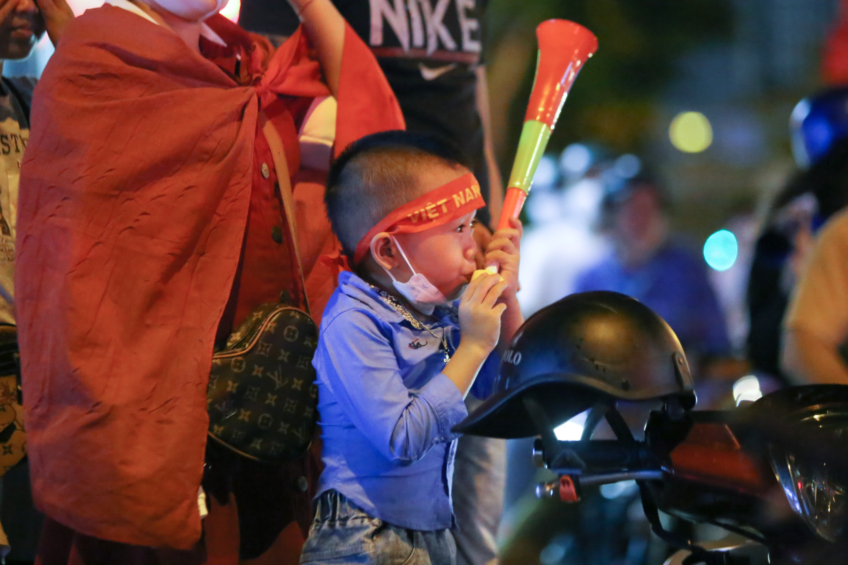 A boy blasts an air horn to celebrate Vietnam's gold medal in men's football at the 31st SEA Games on Ham Nghi Street in District 1, Ho Chi Minh City. Photo: Nguyen Khang / Tuoi Tre