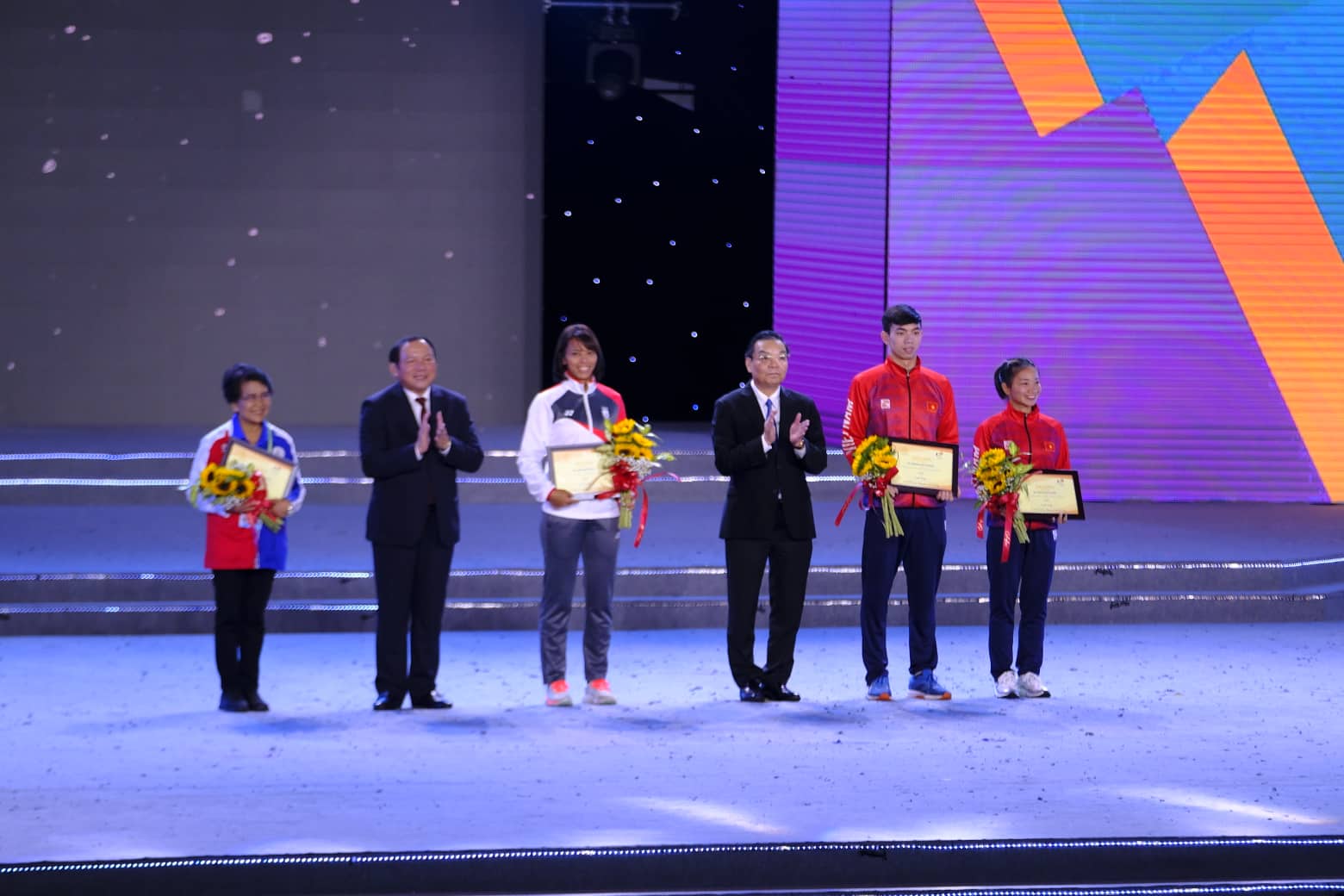 Vietnam’s Nguyen Thi Oanh (R, 1st) and Nguyen Huy Hoang (R, 2nd), a representative of Thailand’s Joshua Robert Atkinson (L), and Singapore’s Jing Wen Quah (R, 3rd) receive honor as the 31st SEA Games’ best athletes at its closing ceremony in Hanoi, May 23, 2022. Photo: Nam Tran / Tuoi Tre