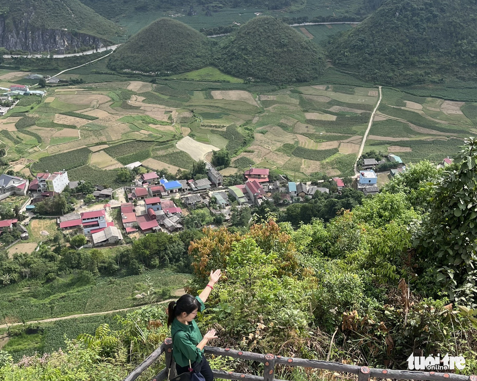 A visitor poses for a photo with the Twin Mountains in the background in Quan Ba District, Ha Giang Province, Vietnam. Photo: Nhu Binh / Tuoi Tre