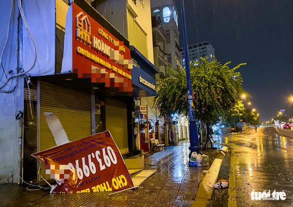 An advertising board lies on the sidewalk in District 4, Ho Chi Minh City in the rain on May 26, 2022. Photo: Chau Tuan / Tuoi Tre