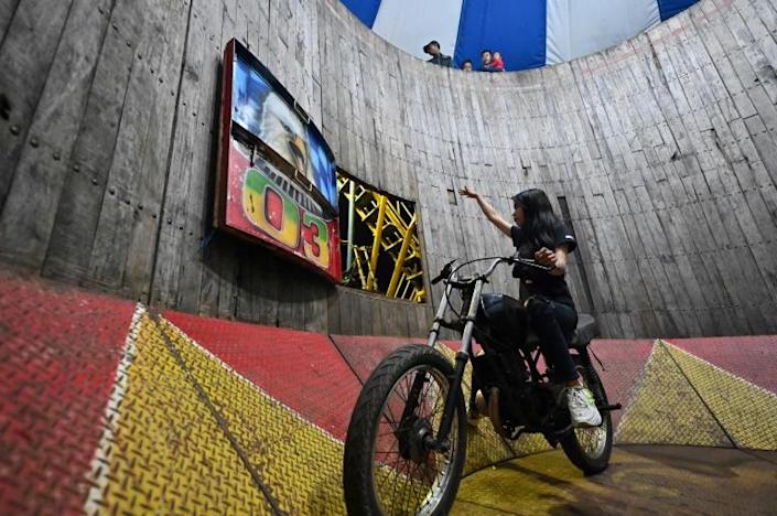 This photo taken on April 30, 2022 shows daredevil Karmila Purba, a rider of the 'wall of death’, locally known as a ‘Tong Setan’, gesturing before a performance inside a six-metre high wall at a night carnival in Bogor. Photo: AFP