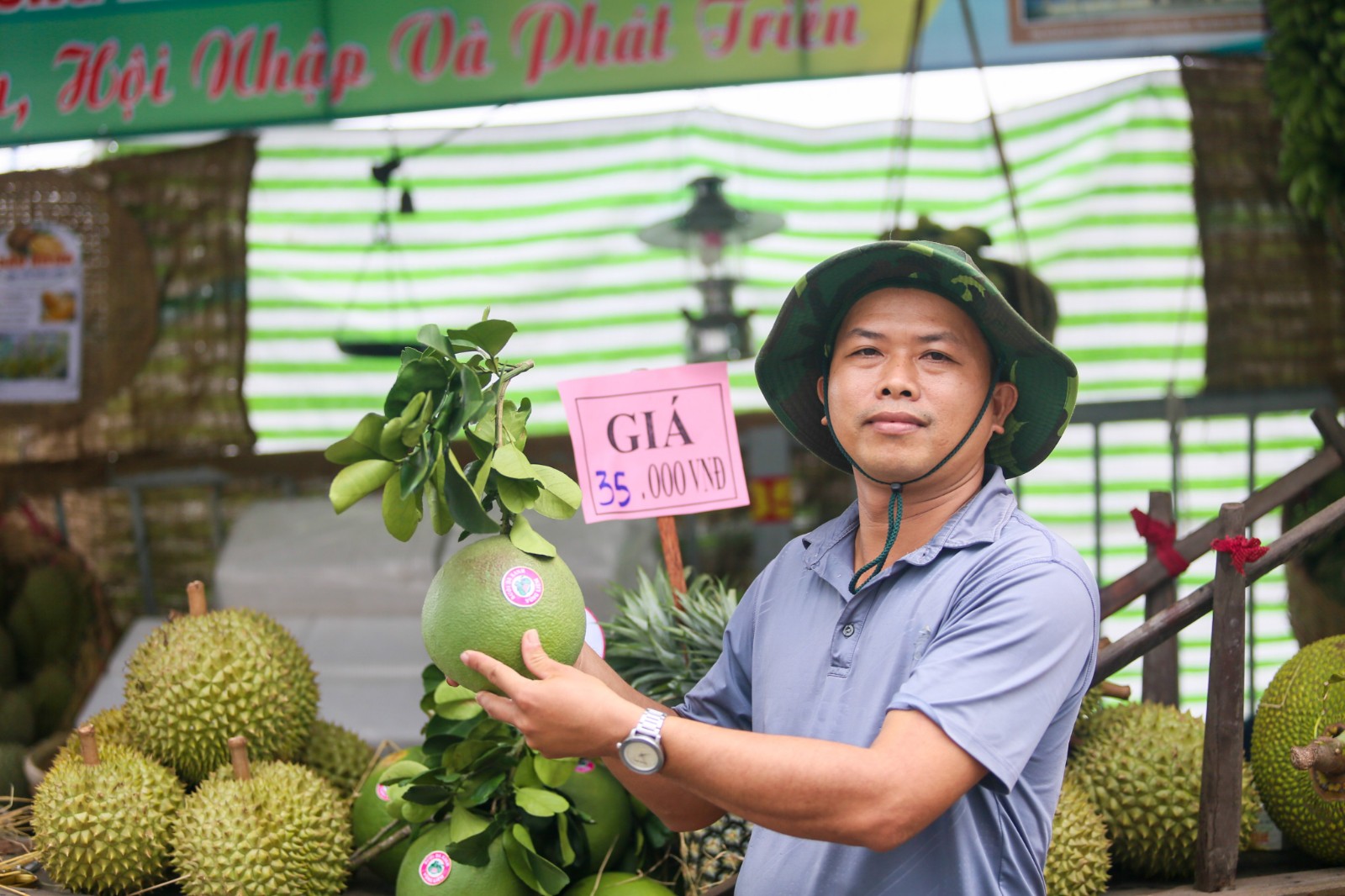 A merchant holds a pomelo at his stall at the ‘Tren ben duoi thuyen’ Fruit Week in District 8, Ho Chi Minh City, May 28, 2022. Photo: Chau Tuan / Tuoi Tre