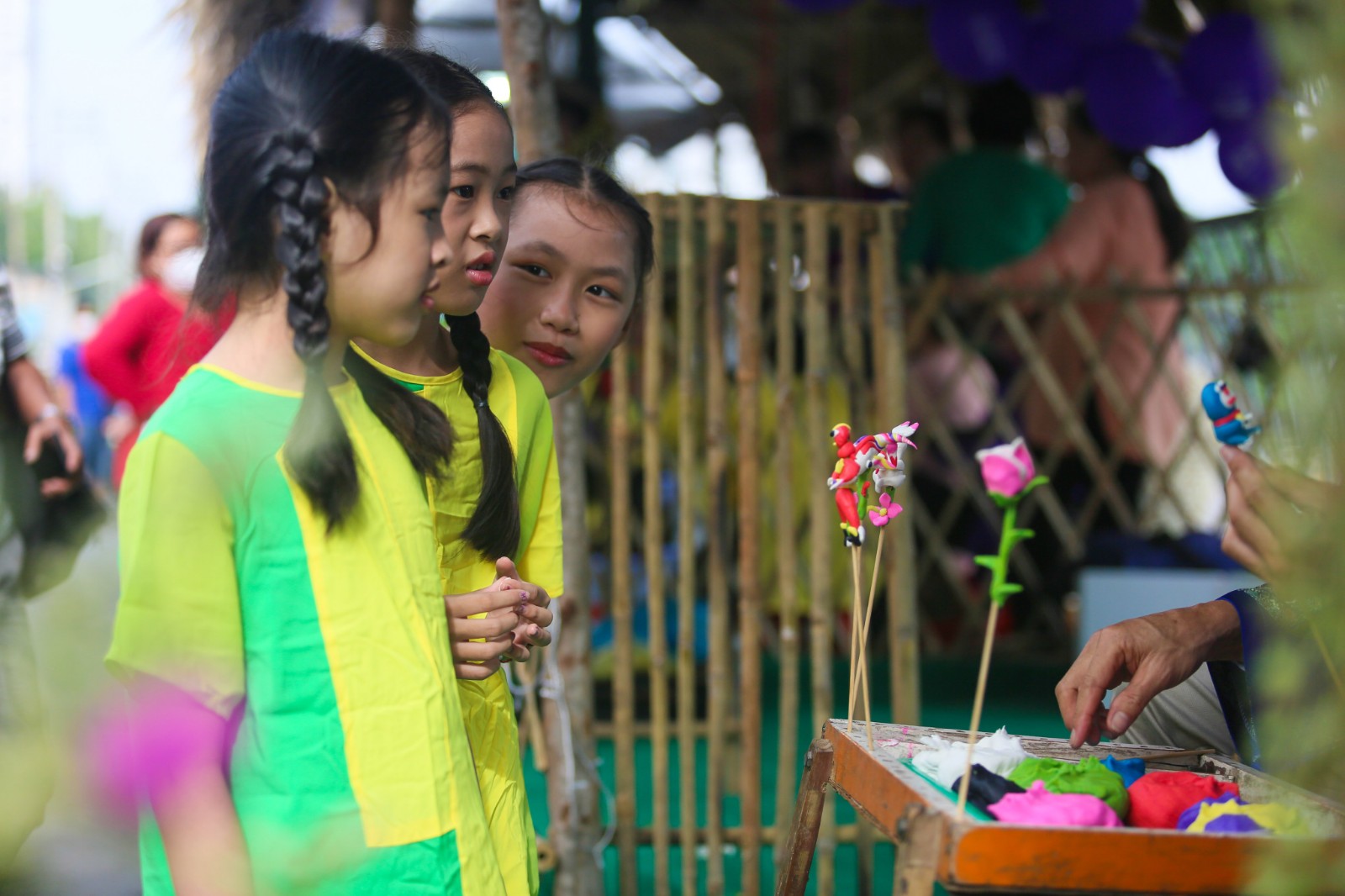 Children watch how to he (edible toy statuettes) are made at the ‘Tren ben duoi thuyen’ Fruit Week in District 8, Ho Chi Minh City, May 28, 2022. Photo: Chau Tuan / Tuoi Tre