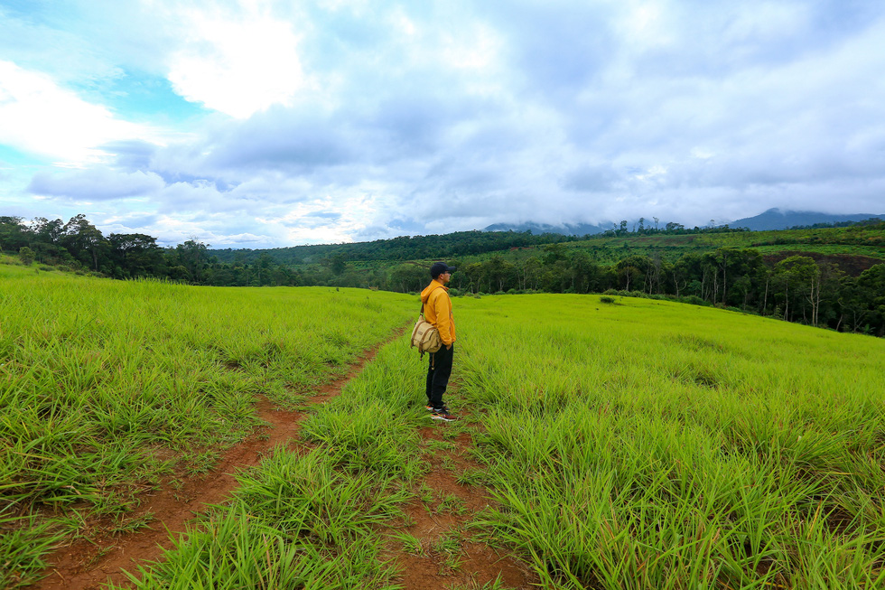 A visitor poses for a photo at a green hill in Mang Den Town, Kon Plong District, Kon Tum Province, Vietnam. Photo: Do Do / Tuoi Tre