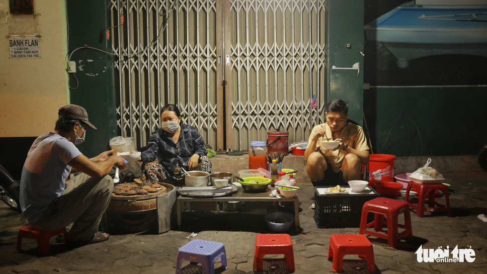 People eat ‘banh can’ at night at a vendor stall in Phan Thiet City, south-central Vietnam. Photo: Ha Manh / Tuoi Tre