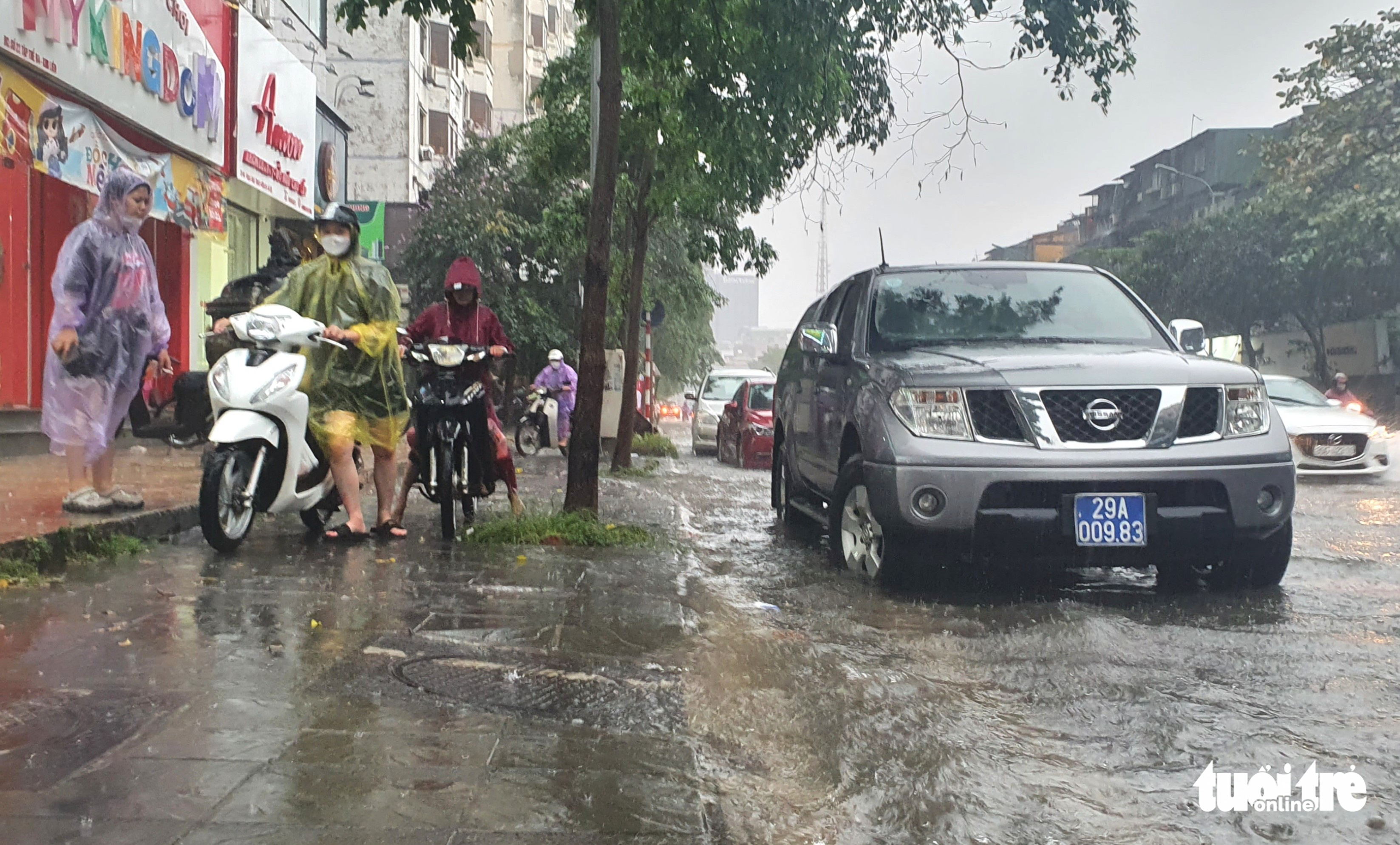 People walk their motorbikes on the sidewalk of flooded Pham Ngoc Thach Street in Dong Da District, Hanoi, May 29, 2022. Photo: Ha Quan / Tuoi Tre