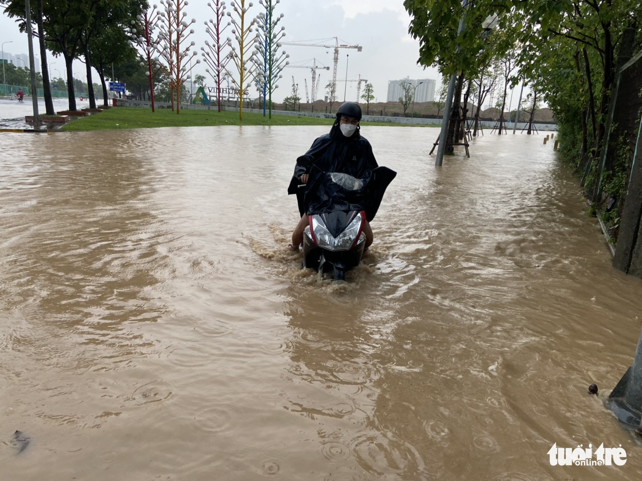 A person rides their motorbike through a flooded area in Nam Tu Liem District, Hanoi, May 29, 2022. Photo: Quang The / Tuoi Tre