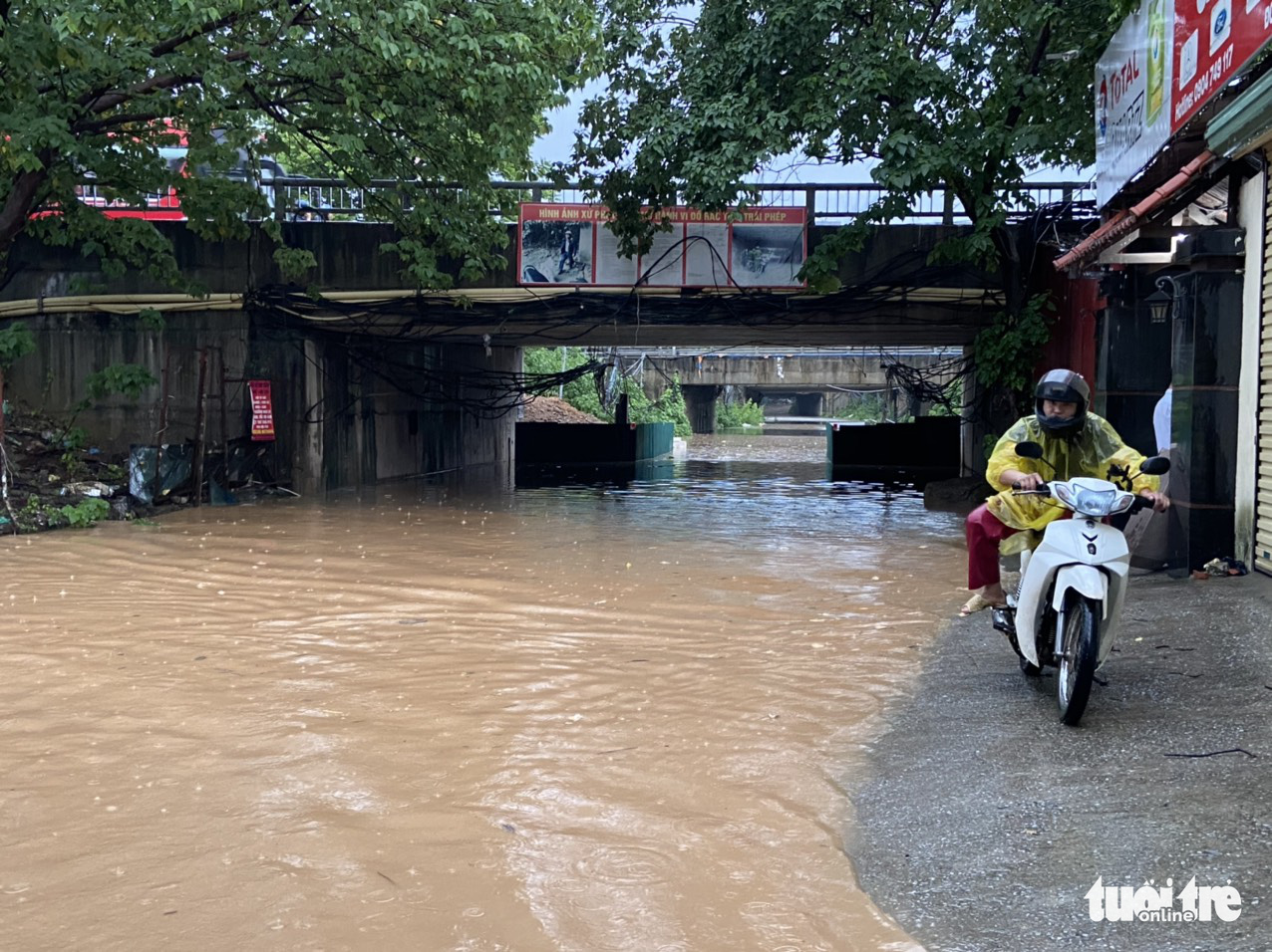 A person rides their motorbike through a flooded area in Nam Tu Liem District, Hanoi, May 29, 2022. Photo: Quang The / Tuoi Tre
