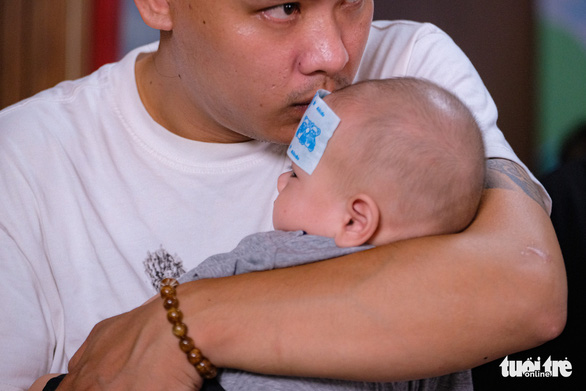 A four-month baby is seen in his father’s arms while under treatment at Thanh Nhan Hospital in Hanoi, Vietnam. Photo: Nam Tran / Tuoi Tre