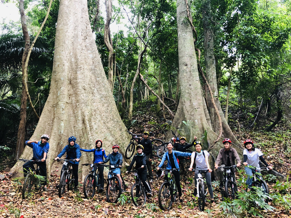A group of cyclists pose for a photo at a hundred-year-old tree, a famous checkpoint along the route. Photo: Vi Thich / Handout via Tuoi Tre