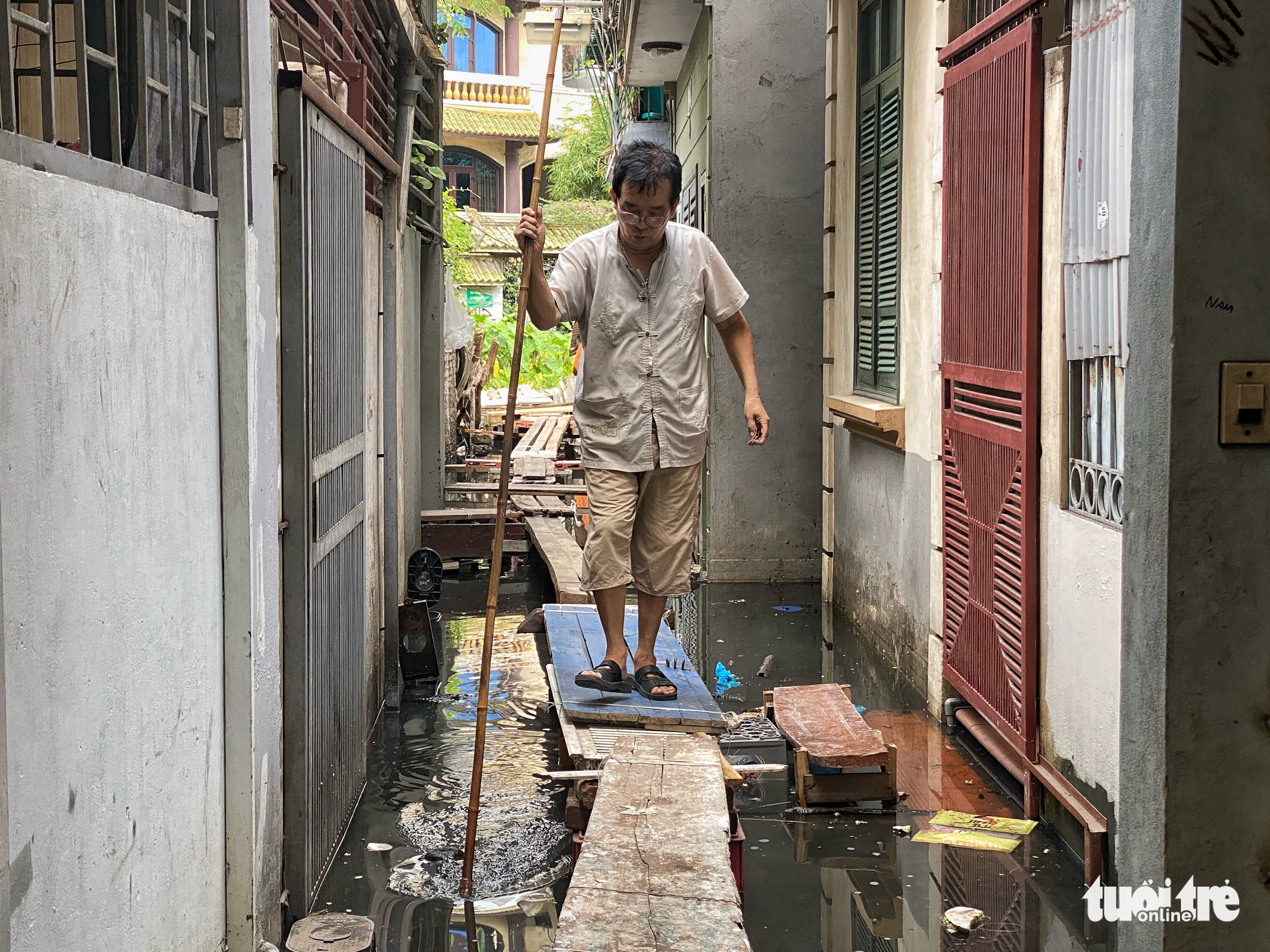 A resident walks on a makeshift bridge in a flooded alley in Tay Ho District, Hanoi. Photo: Pham Tuan / Tuoi Tre