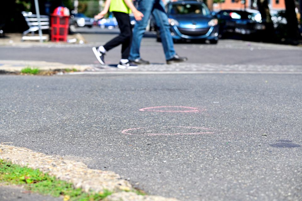 People walk past police markings at a crime scene after a deadly mass shooting on South Street, at the intersection of Bainbridge St and S 4th St, in Philadelphia, Pennsylvania, U.S., June 5, 2022. Photo: Reuters