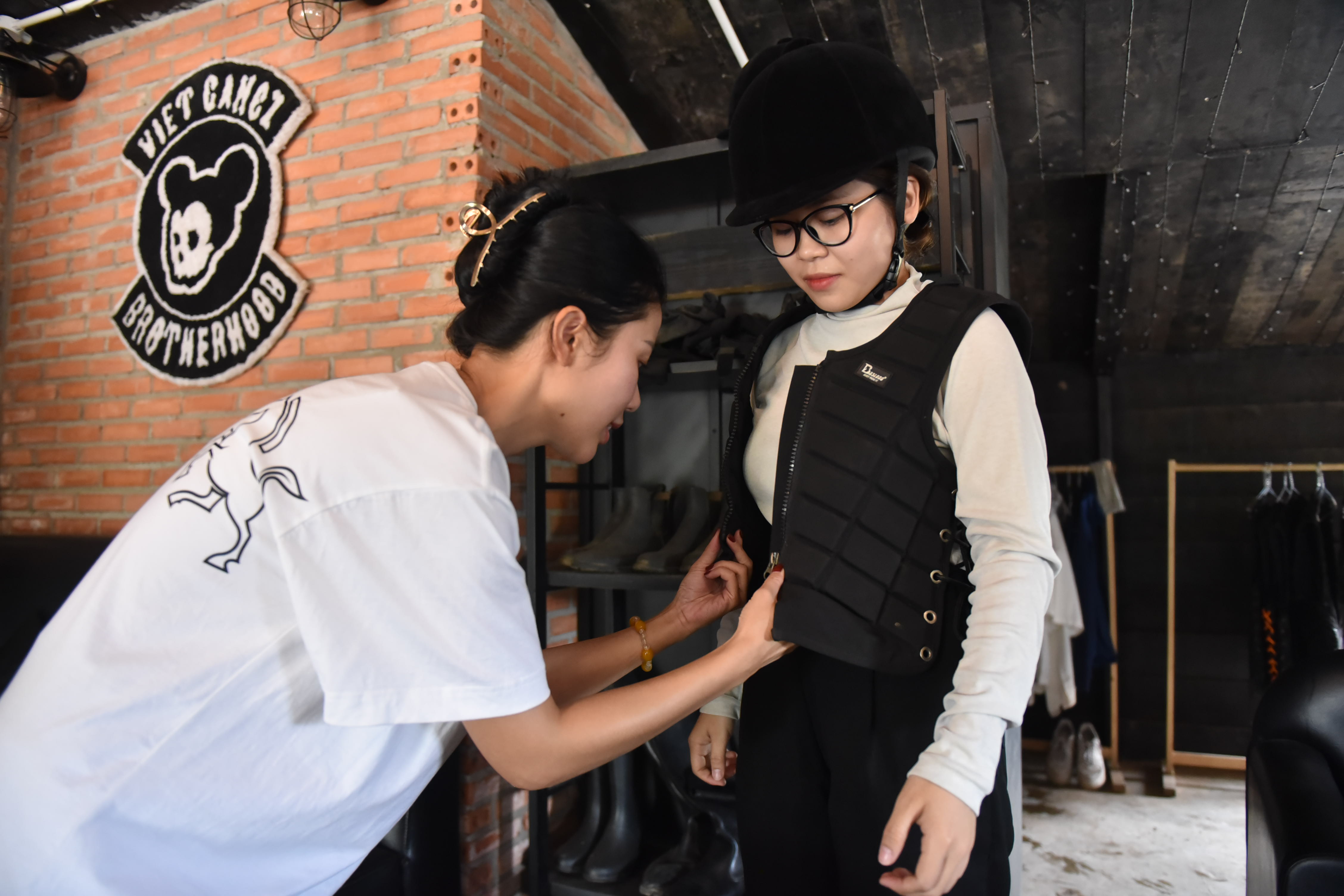 A staff member helps a rider put on safety equipment before mounting a horse at Vietgangz Horse Club, Thu Duc City. Photo: Ngoc Phuong / Tuoi Tre News