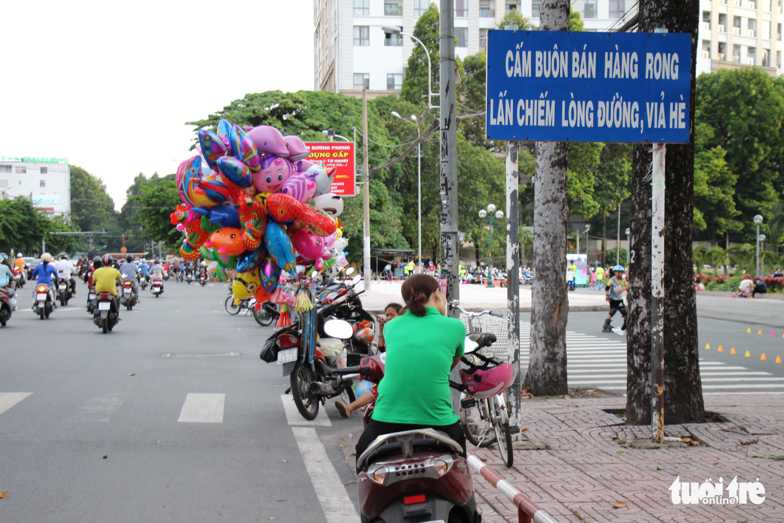 A balloon street vendor and a woman illegally park their motorbikes on Hoang Minh Giam Street in Phu Nhuan District, Ho Chi Minh City. Photo: Phuong Quyen / Tuoi Tre
