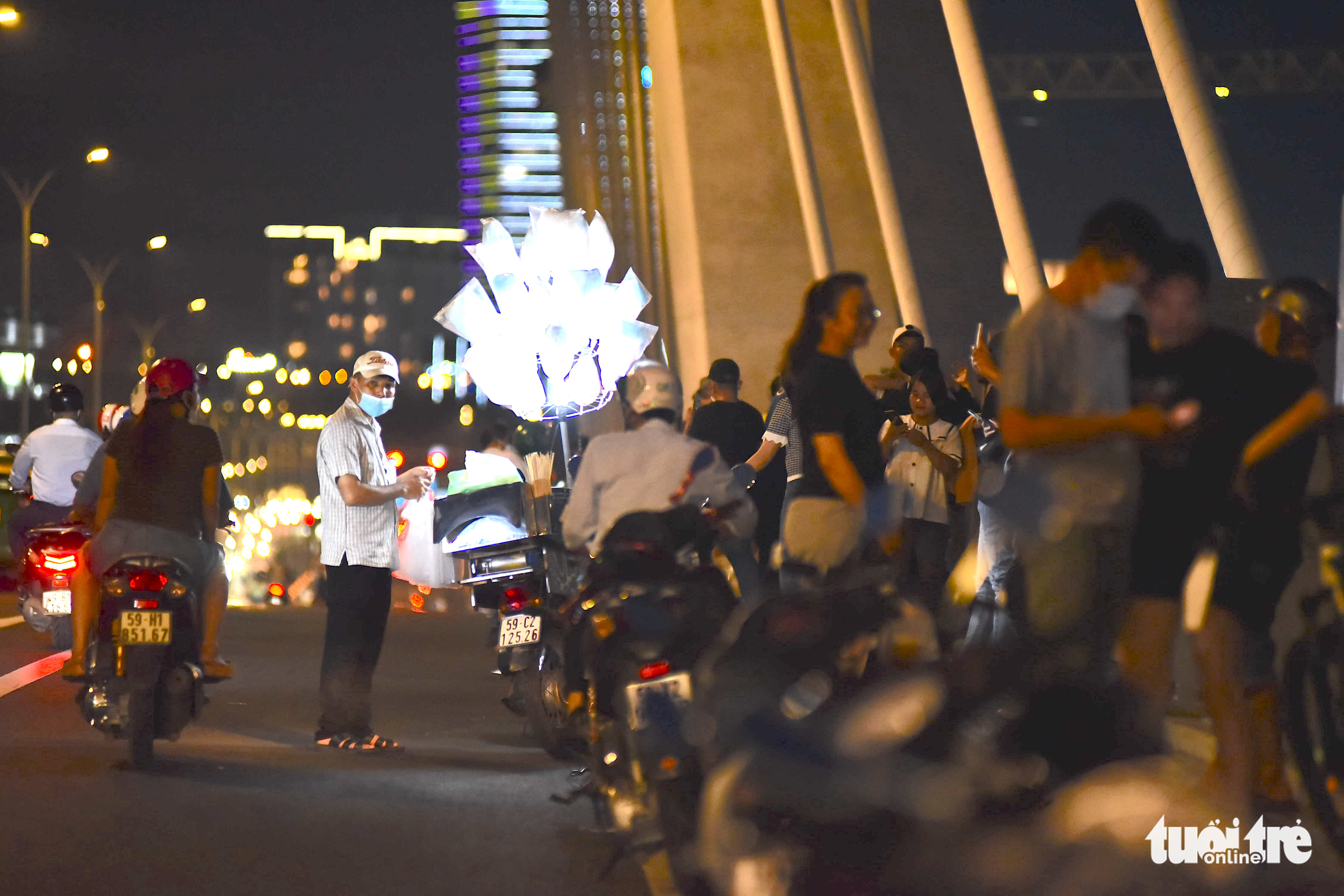 A candy street vendor and people illegally park their motorbikes on the Thu Thiem 2 Bridge in District 1, Ho Chi Minh City. Photo: Ngoc Phuong / Tuoi Tre