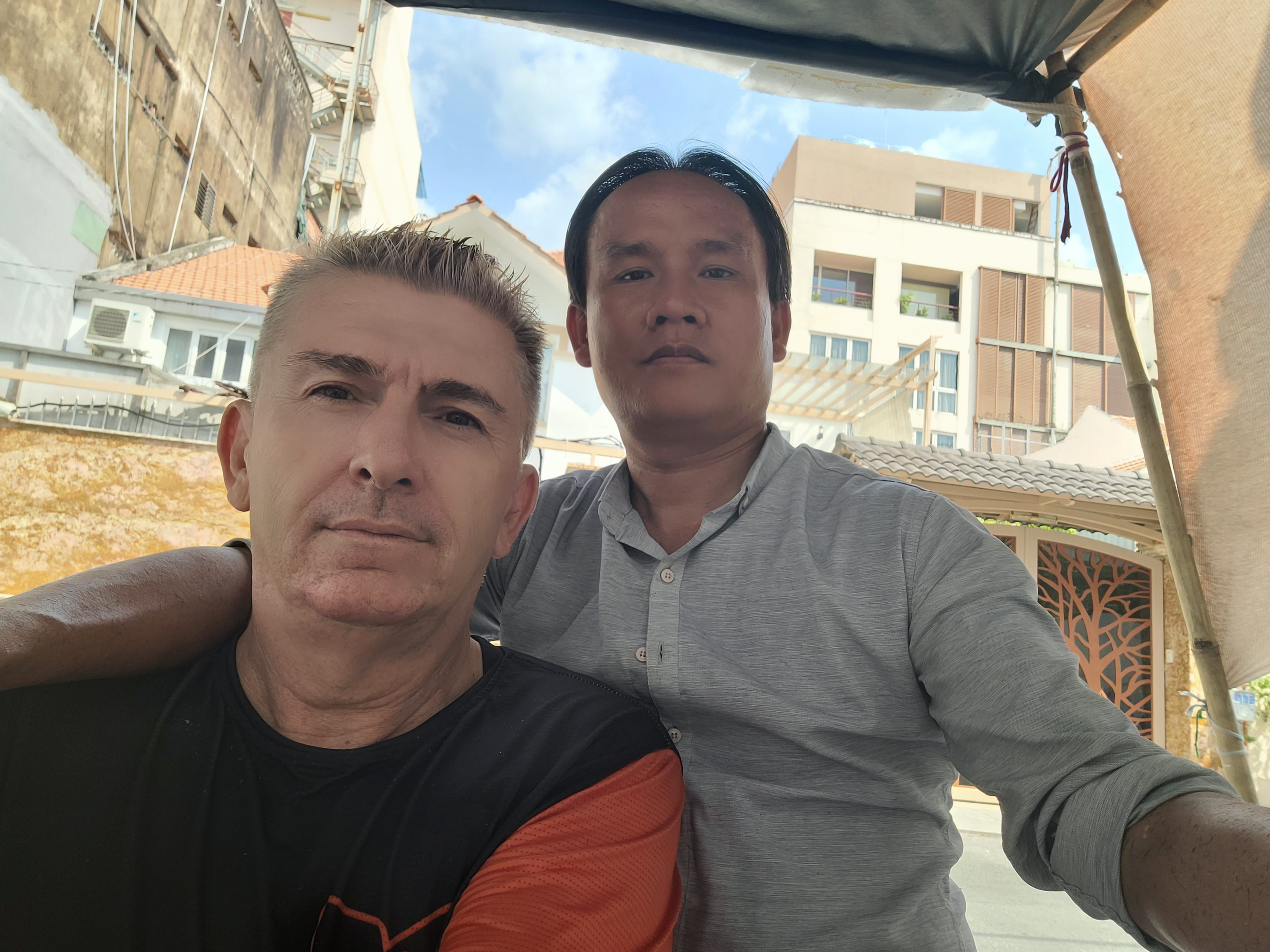 Ray Kuschert and Vinh, owner of a a barber shop on the street in Ho Chi Minh City pose for a selfie.