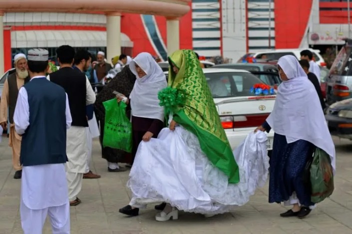 Dozens of Afghan women concealed in thick green shawls were married off in an austere mass wedding in Kabul. Photo: AFP