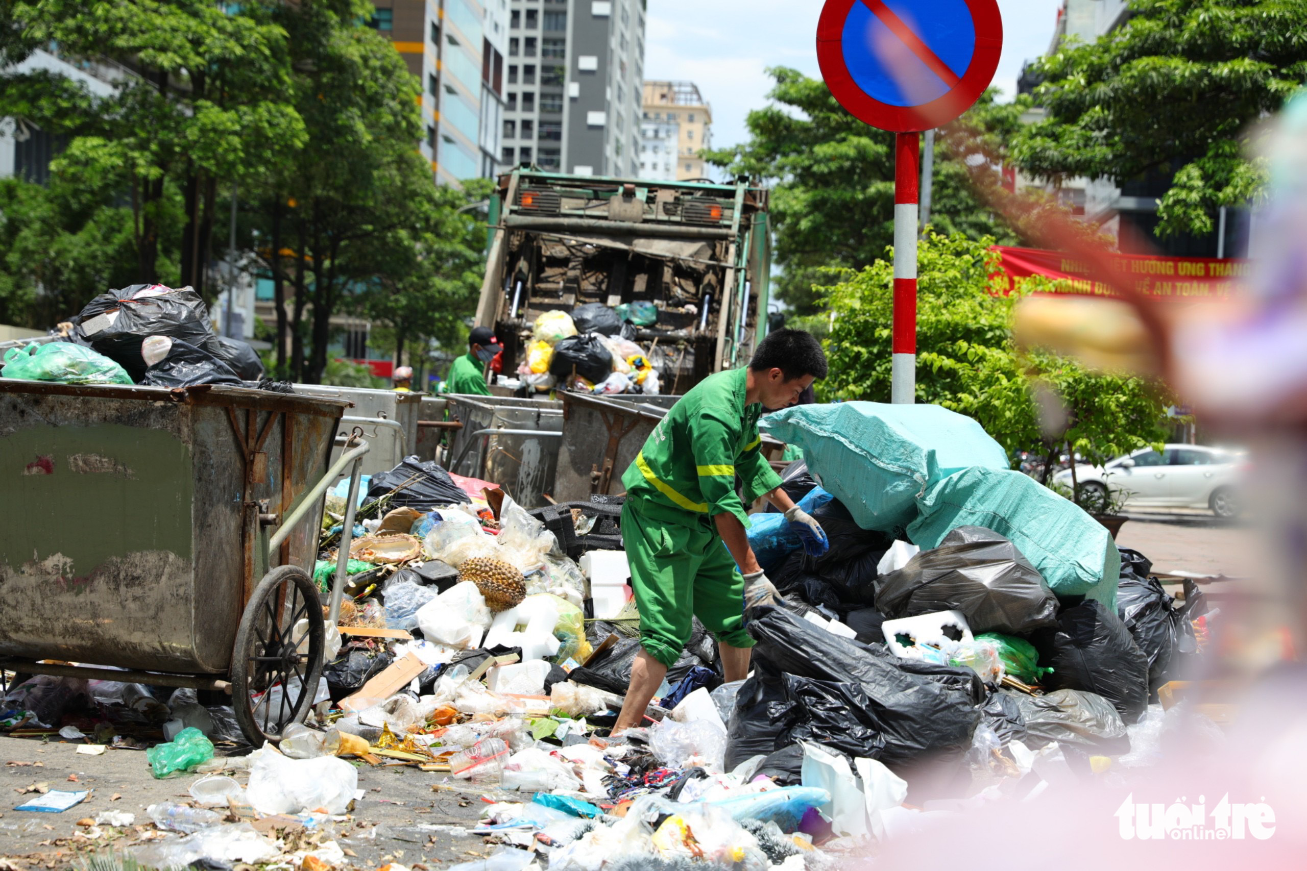 An environment worker collects garbage cart piling up on a street in Cau Giay District, Hanoi, June 17, 2022. Photo: Danh Khang / Tuoi Tre