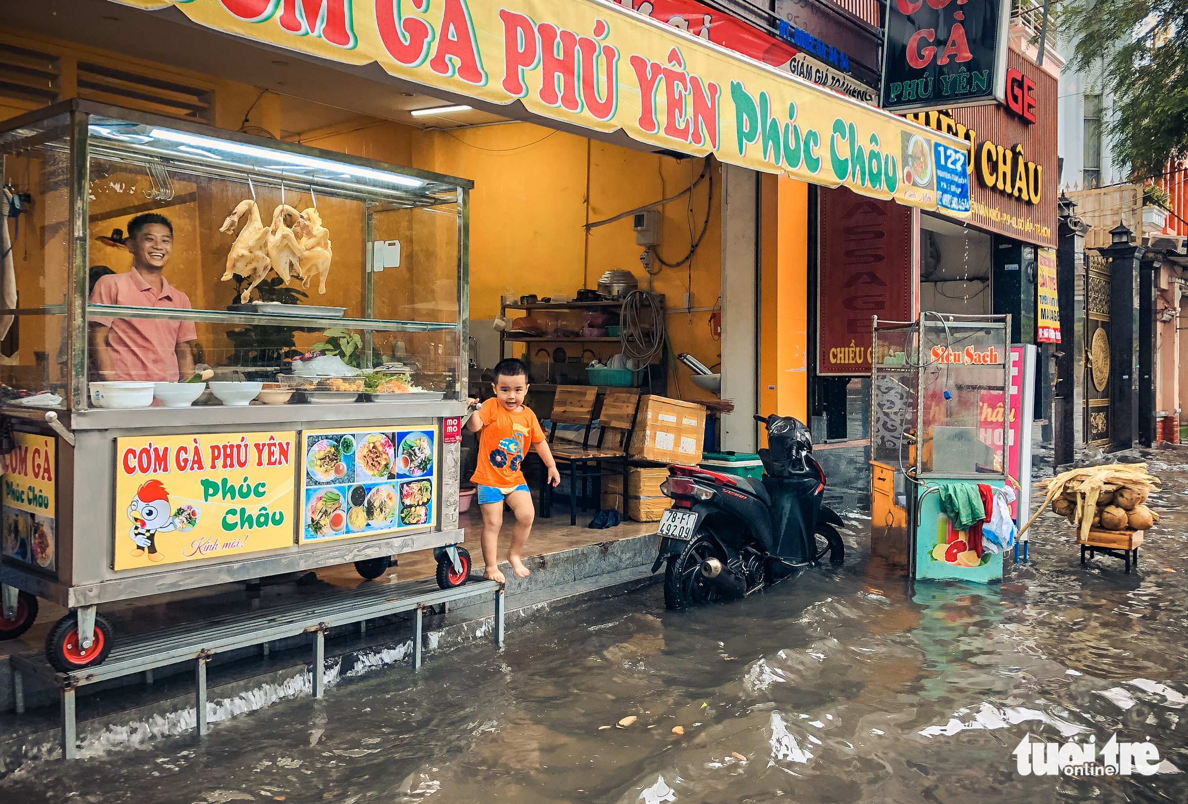 The sidewalk in front of a diner is submerged by rainwater in Ho Chi Minh City, July 20, 2022. Photo: Chau Tuan / Tuoi Tre