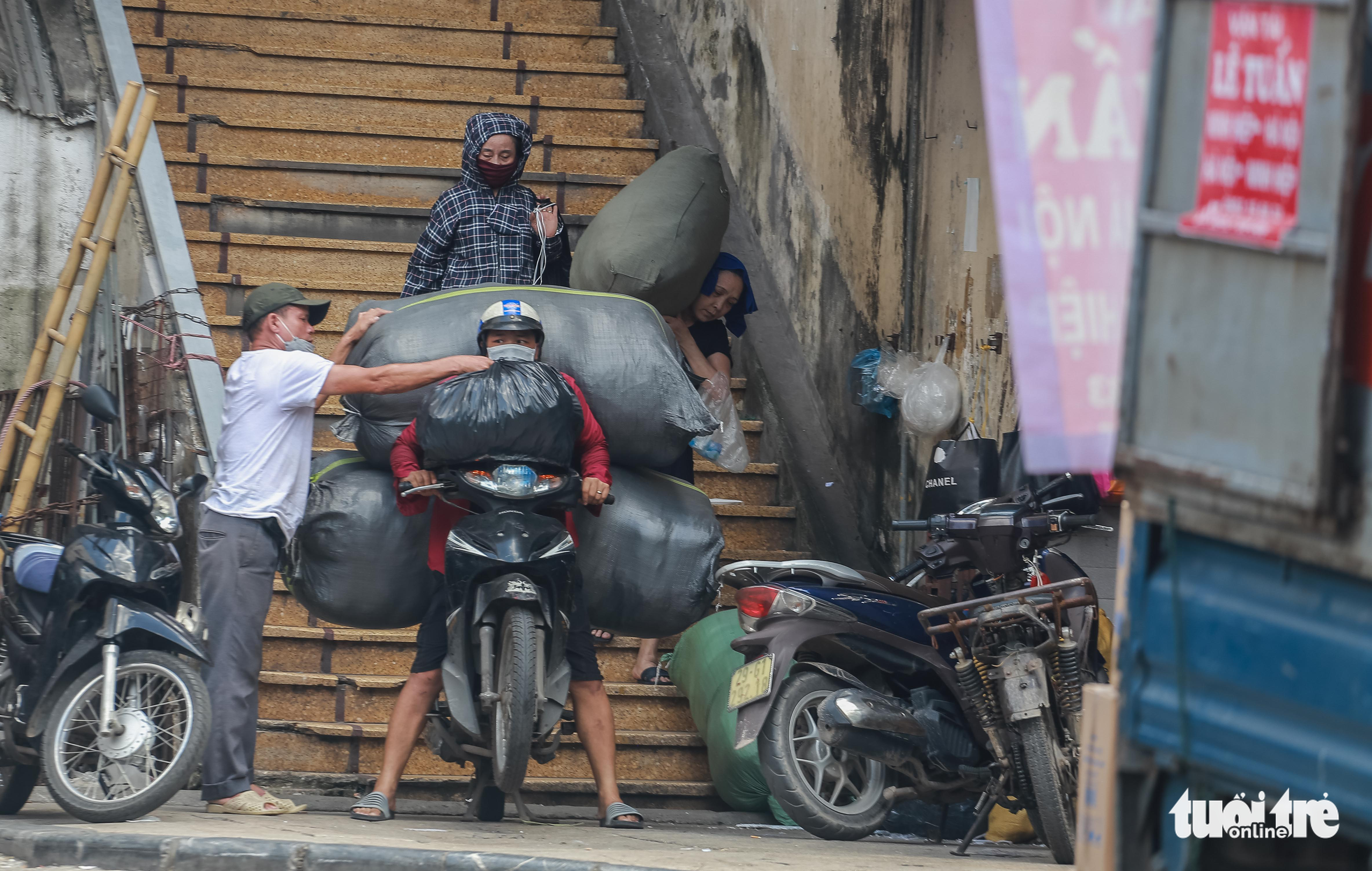 A man transports a large amount of goods on a motorbike in Hanoi, June 21, 2022. Photo: Pham Tuan / Tuoi Tre