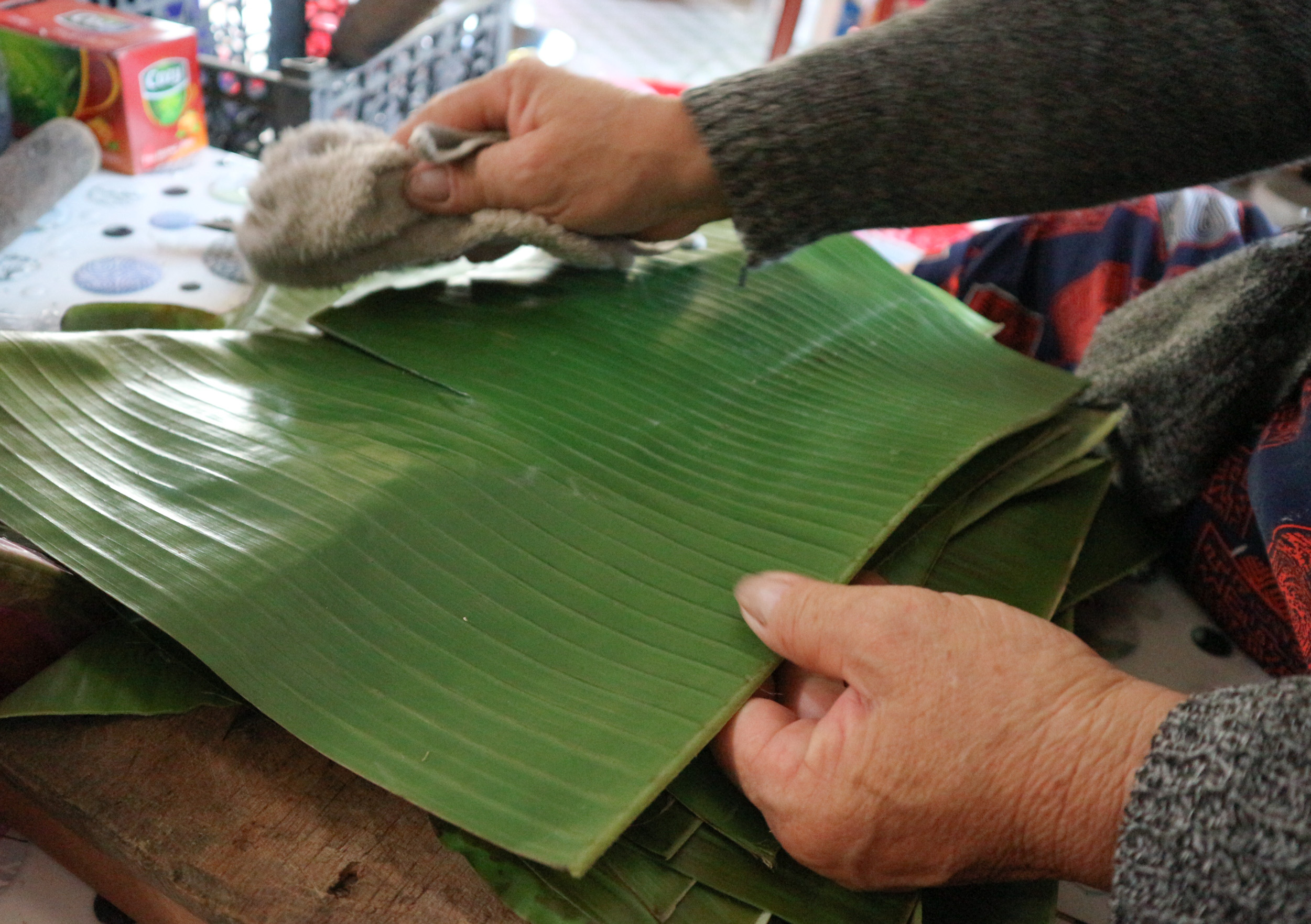 The banana leaves are cut into pieces and cleaned after they are scorched. Photo: Ngoc Phuong / Tuoi Tre News