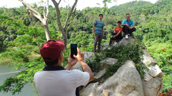 A tourist takes photo of his friends at Thanh Long Lake in Cam Mountain in An Giang Province, Vietnam. Photo: Dang Tuyet / Tuoi Tre