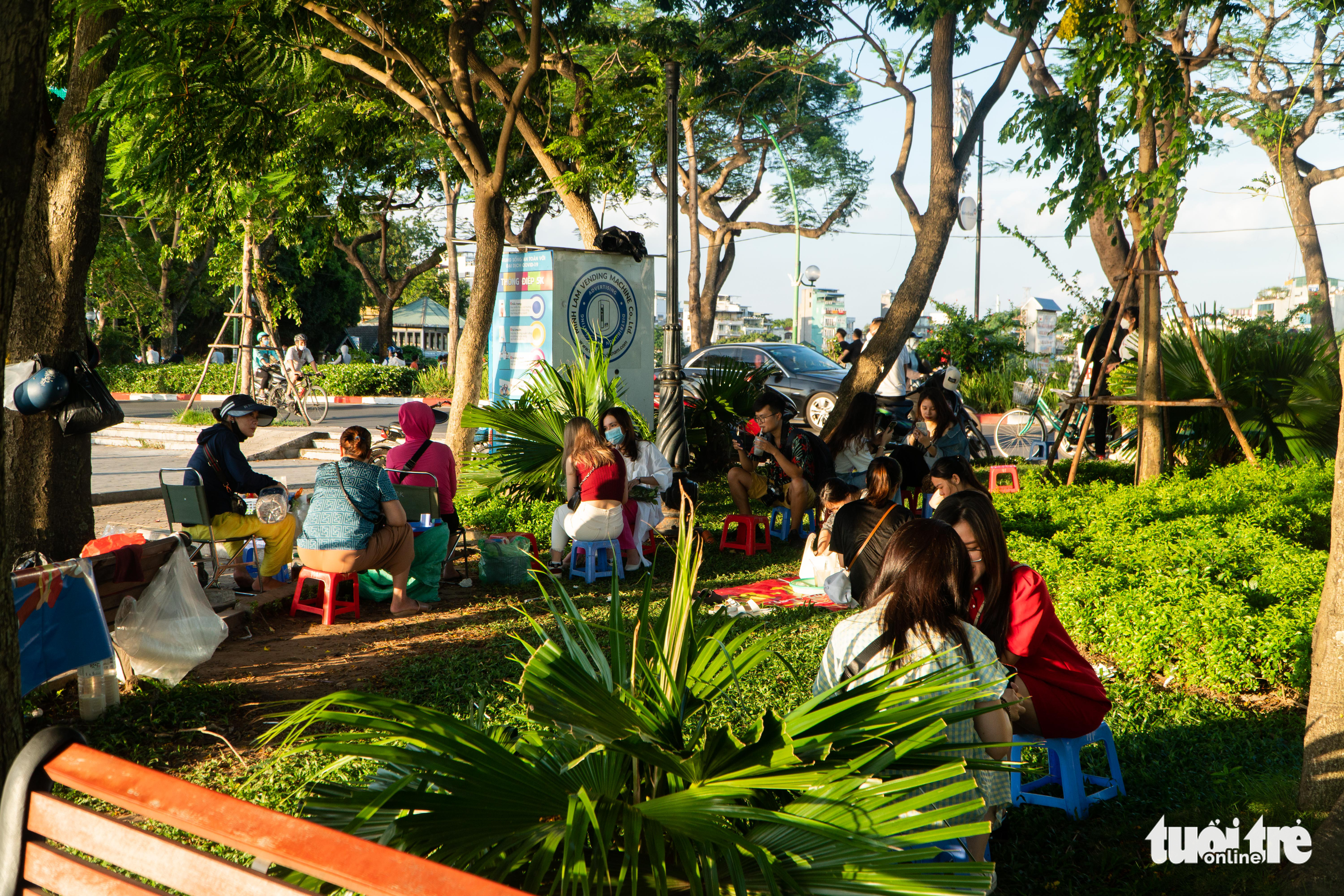 Young people enjoy beverages at a street stall illegally established on the sidewalk garden of a street along the West Lake in Tay Ho District, Hanoi, June 25, 2022. Photo: Pham Tuan / Tuoi Tre