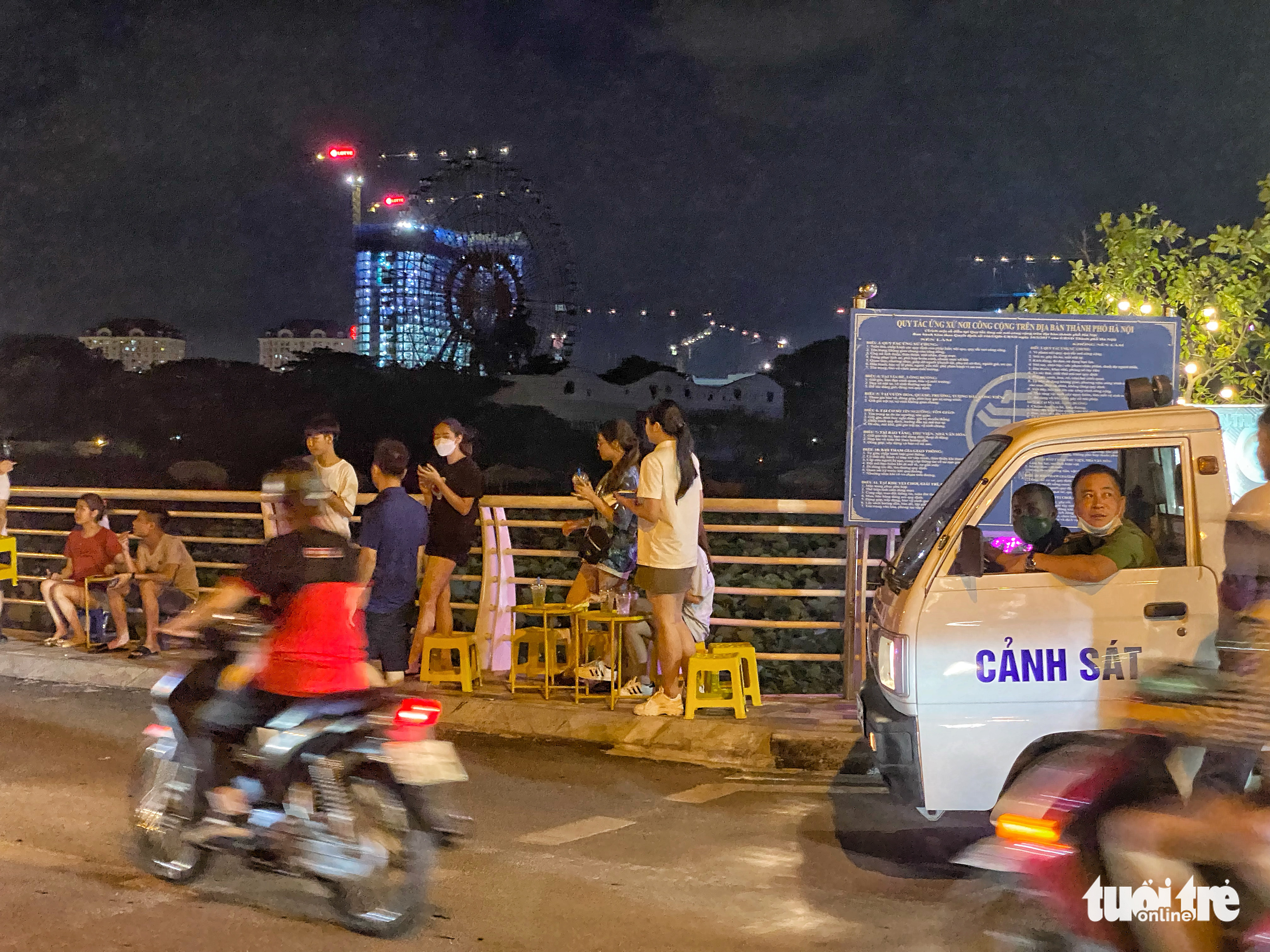 A police patrol truck passes a street stall illegally established on the sidewalk of a street along the West Lake in Tay Ho District, Hanoi, June 25, 2022. Photo: Pham Tuan / Tuoi Tre