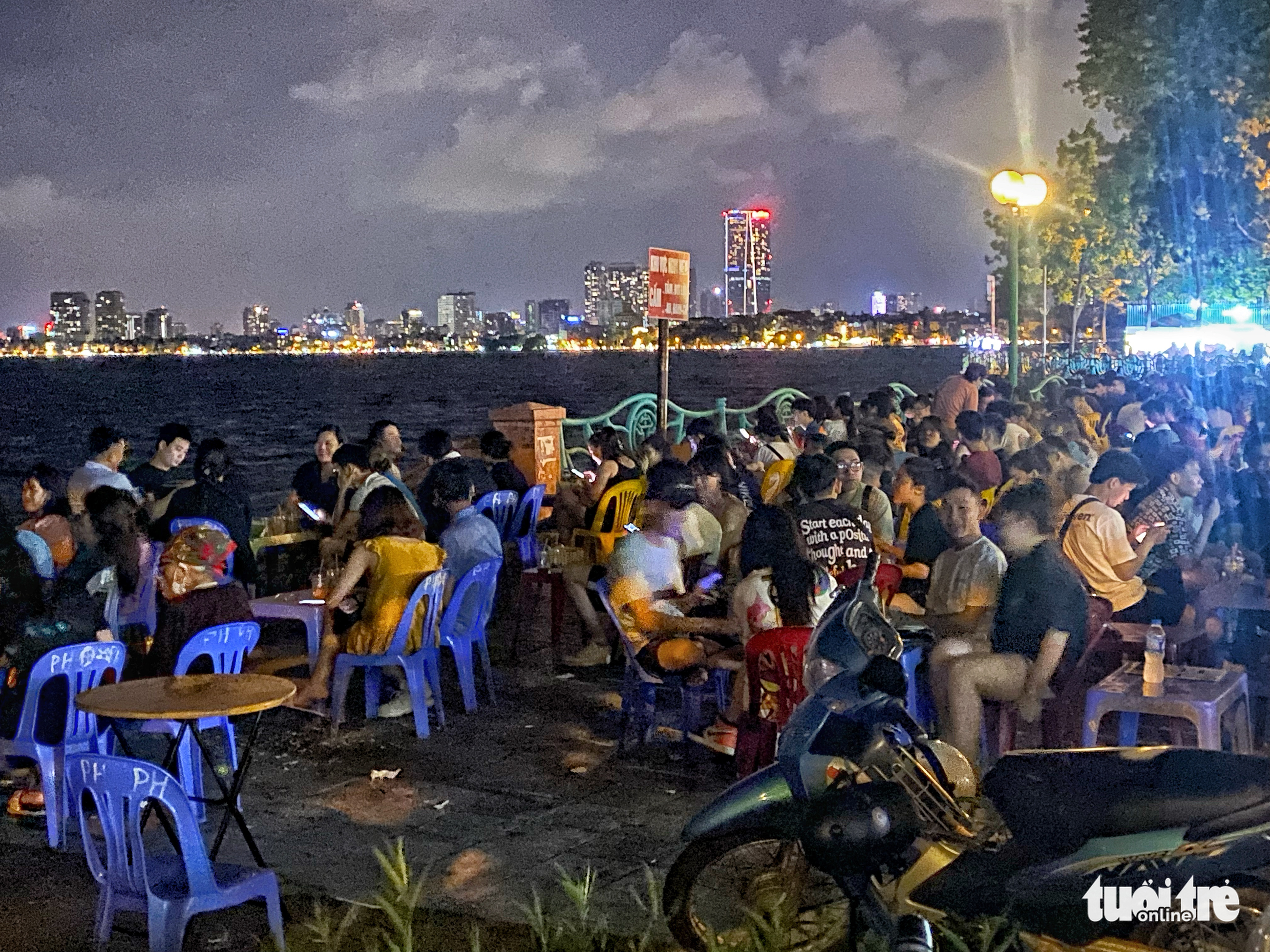 Young people enjoy beverages at a street stall illegally established on the sidewalk of a street along the West Lake in Tay Ho District, Hanoi, June 25, 2022. Photo: Pham Tuan / Tuoi Tre