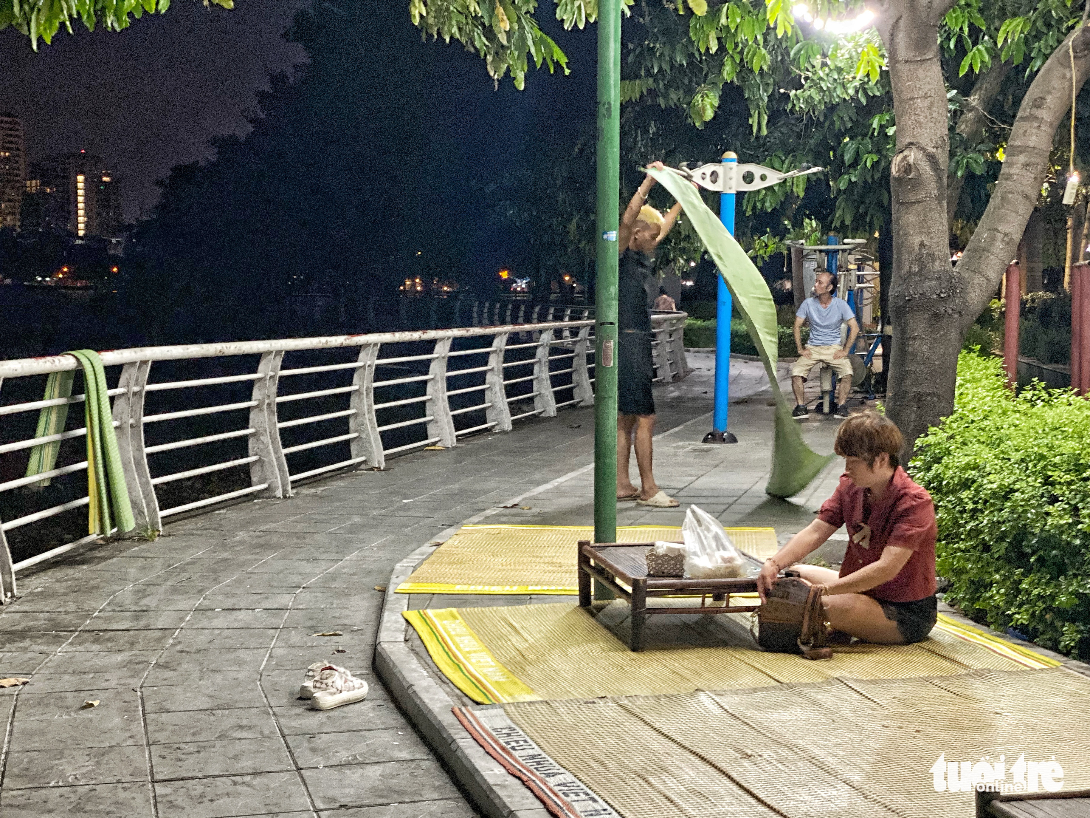 A street vendor sets up mats on the sidewalk of a street along the West Lake to sell beverages in Tay Ho District, Hanoi, June 25, 2022. Photo: Pham Tuan / Tuoi Tre